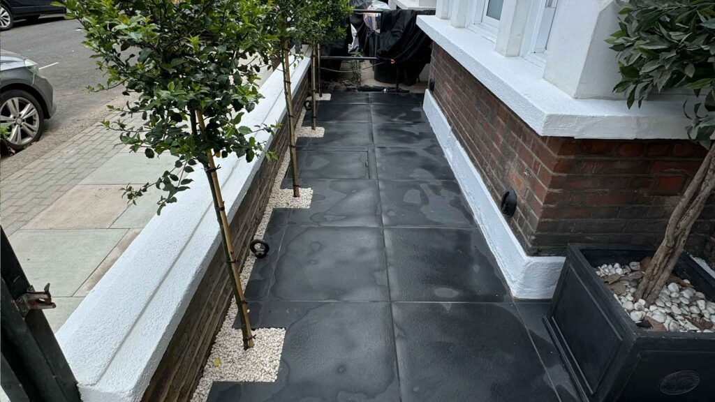 Large format dark porcelain tiles in modern Battersea front garden with standard bay trees