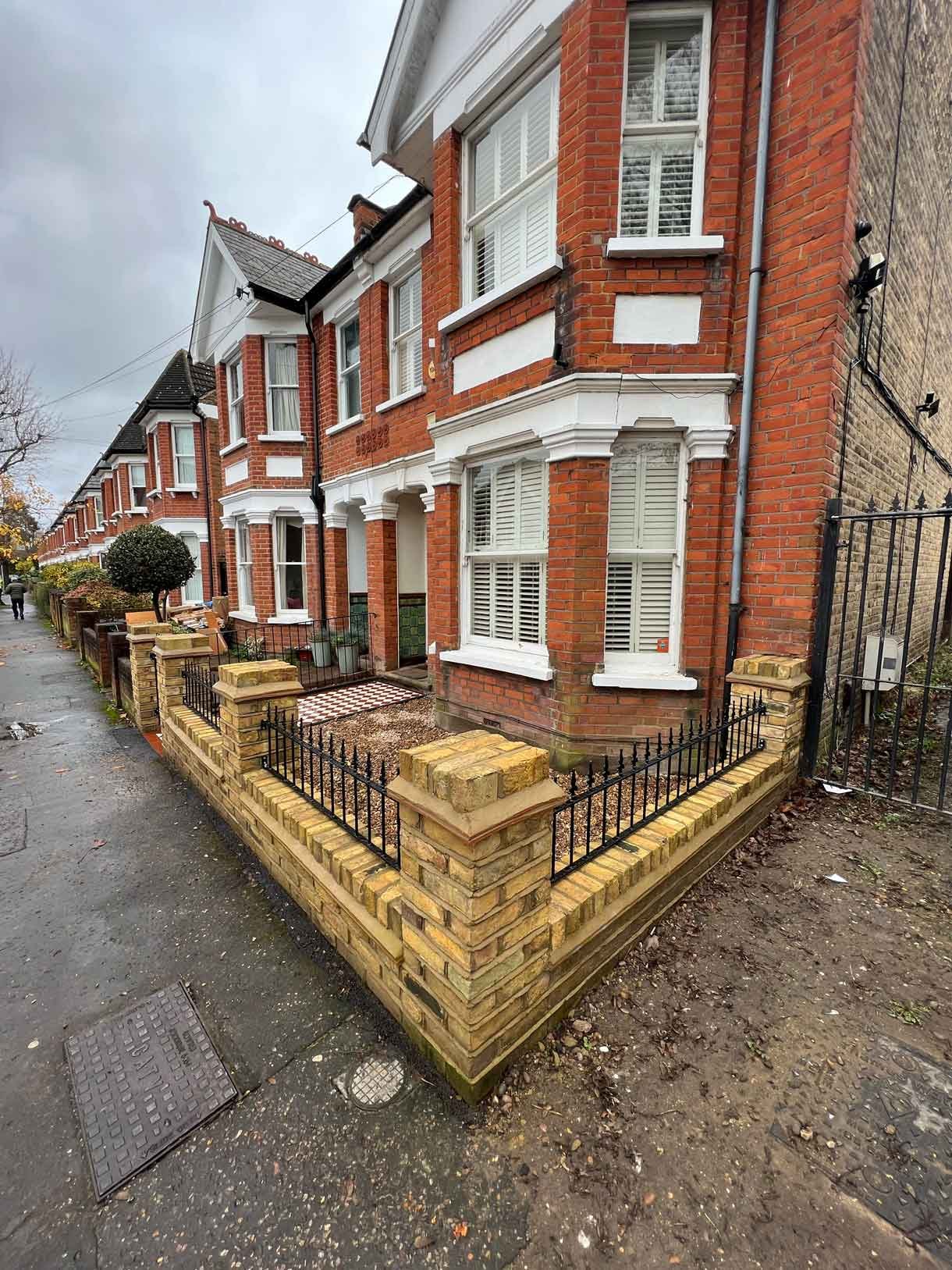A yellow brick wall and a red and white victorian path in checkerboard style.