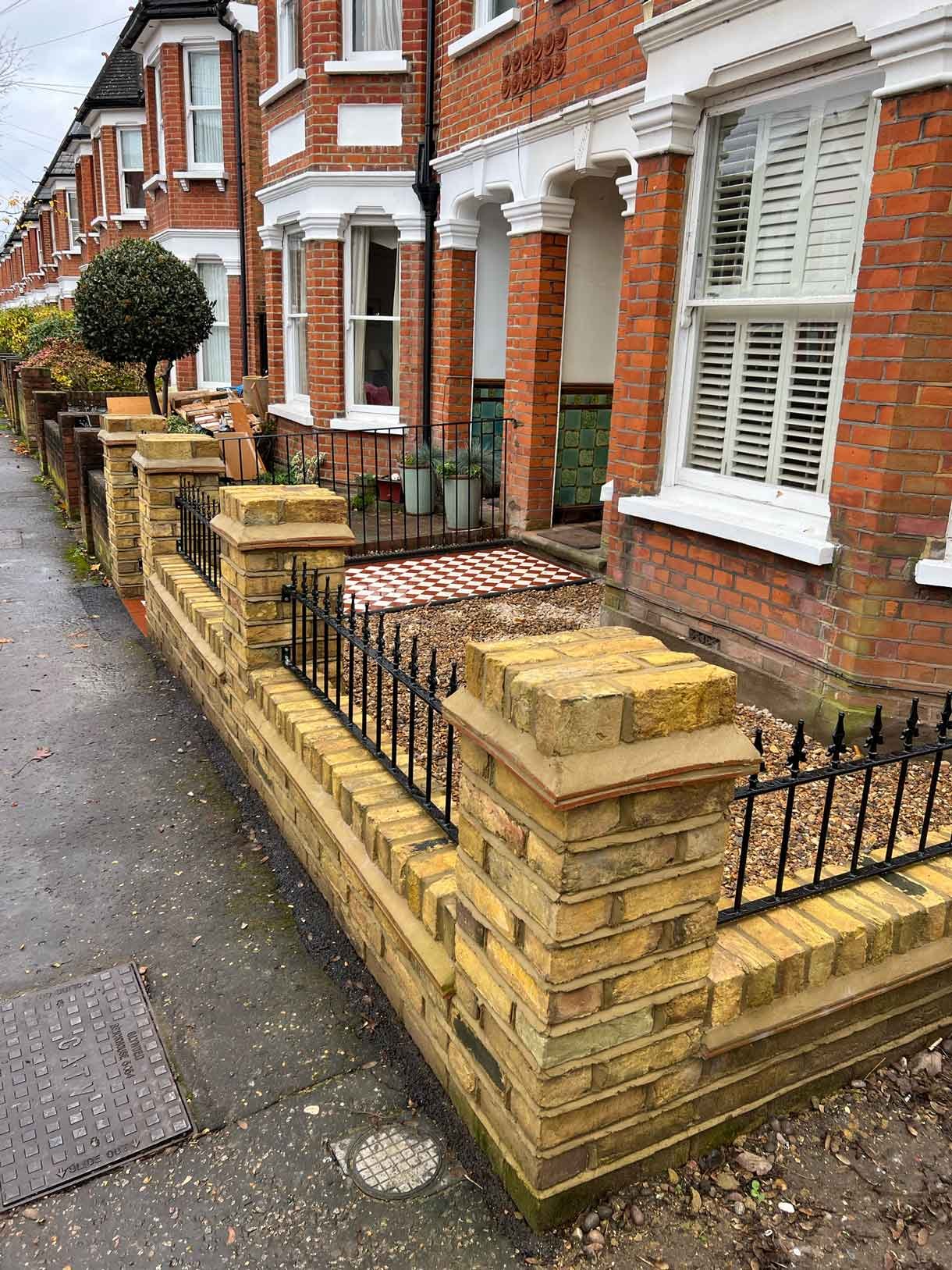 A yellow brick wall and a red and white victorian path in checkerboard style.