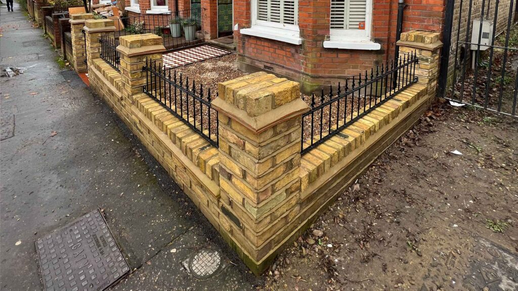 Reclaimed yellow stock brick garden wall with traditional ironwork railings