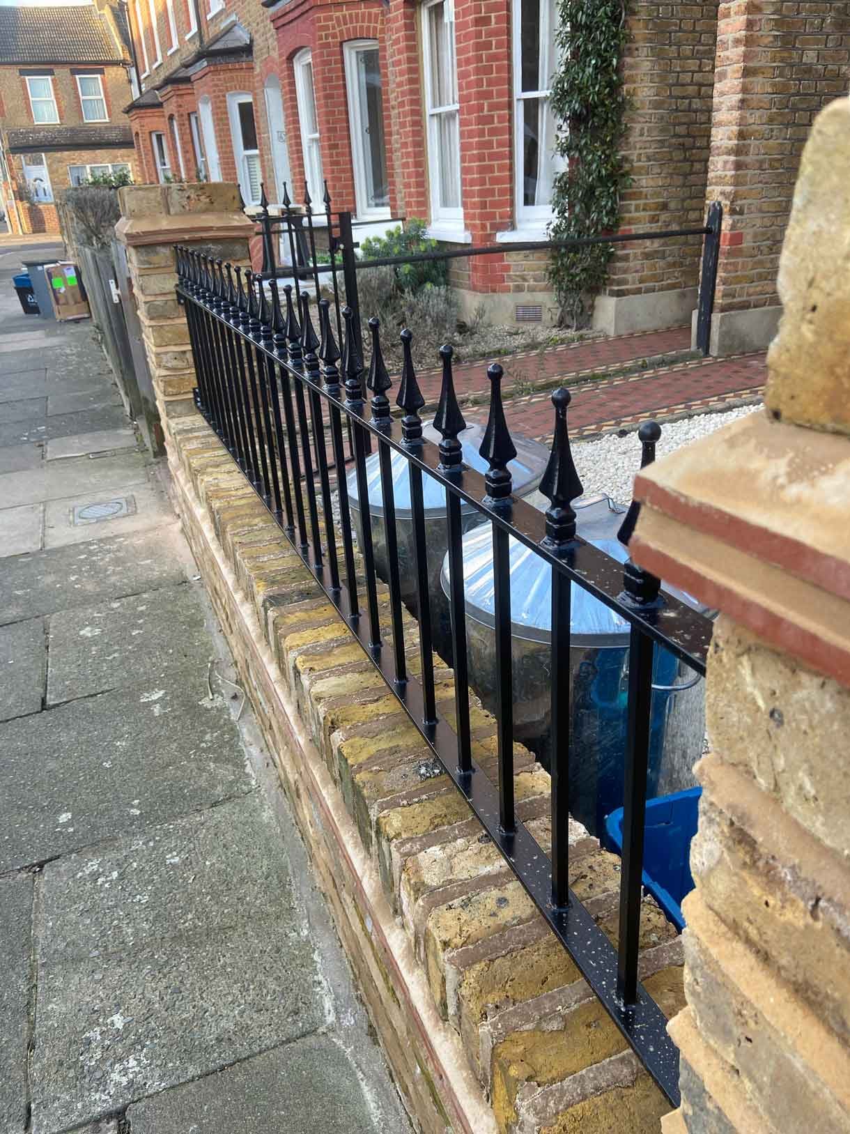 Brick wall using London stock yellow bricks with railings on top and a gate.