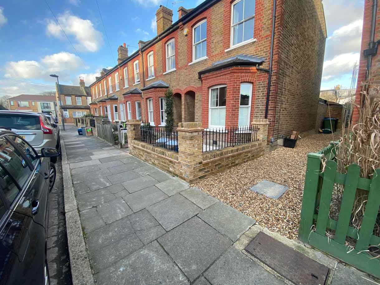 Brick wall using London stock yellow bricks with railings on top and a gate.