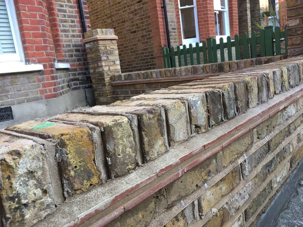 Brick wall using London stock yellow bricks with railings on top and a gate.