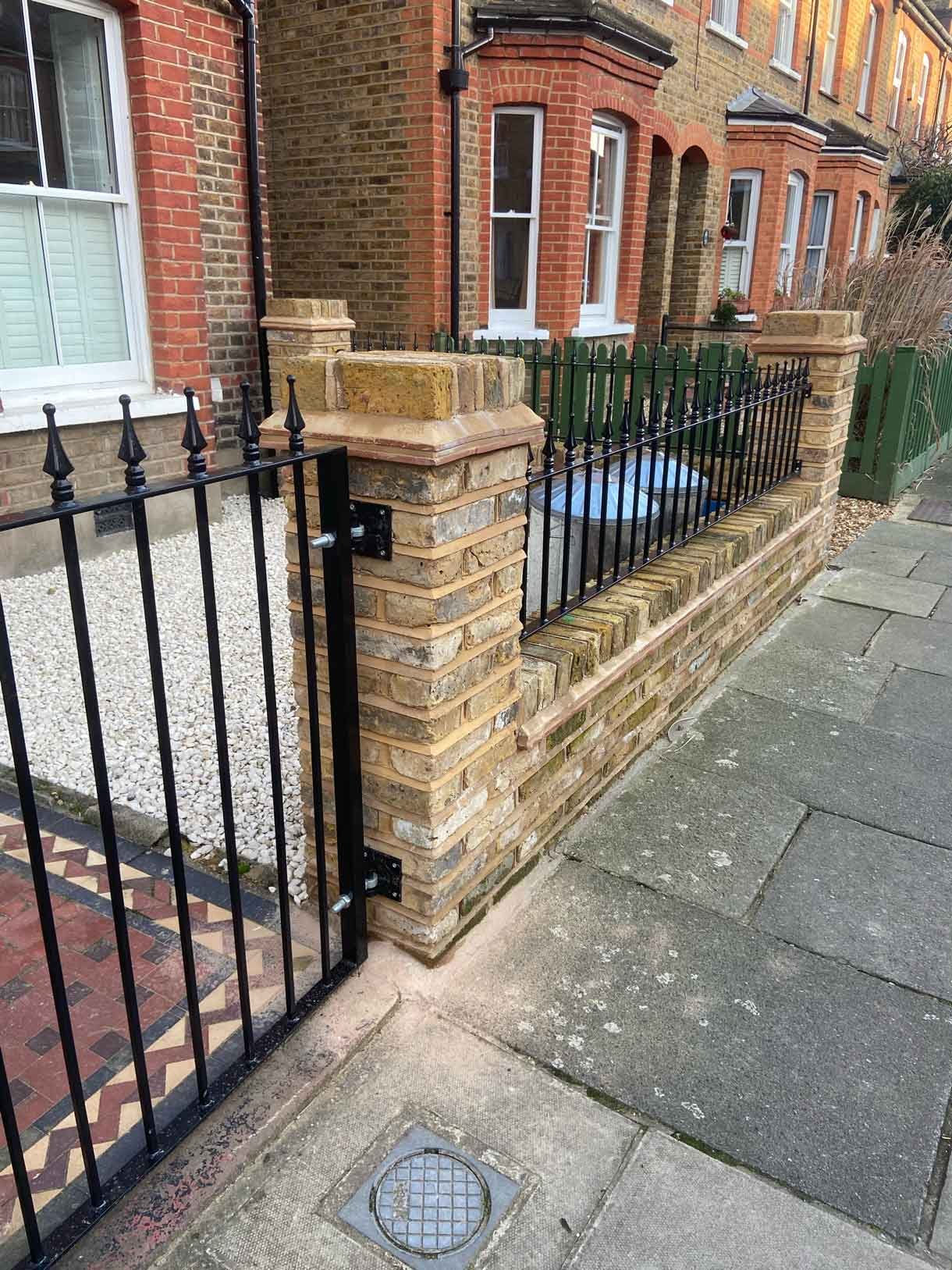 Brick wall using London stock yellow bricks with railings on top and a gate.