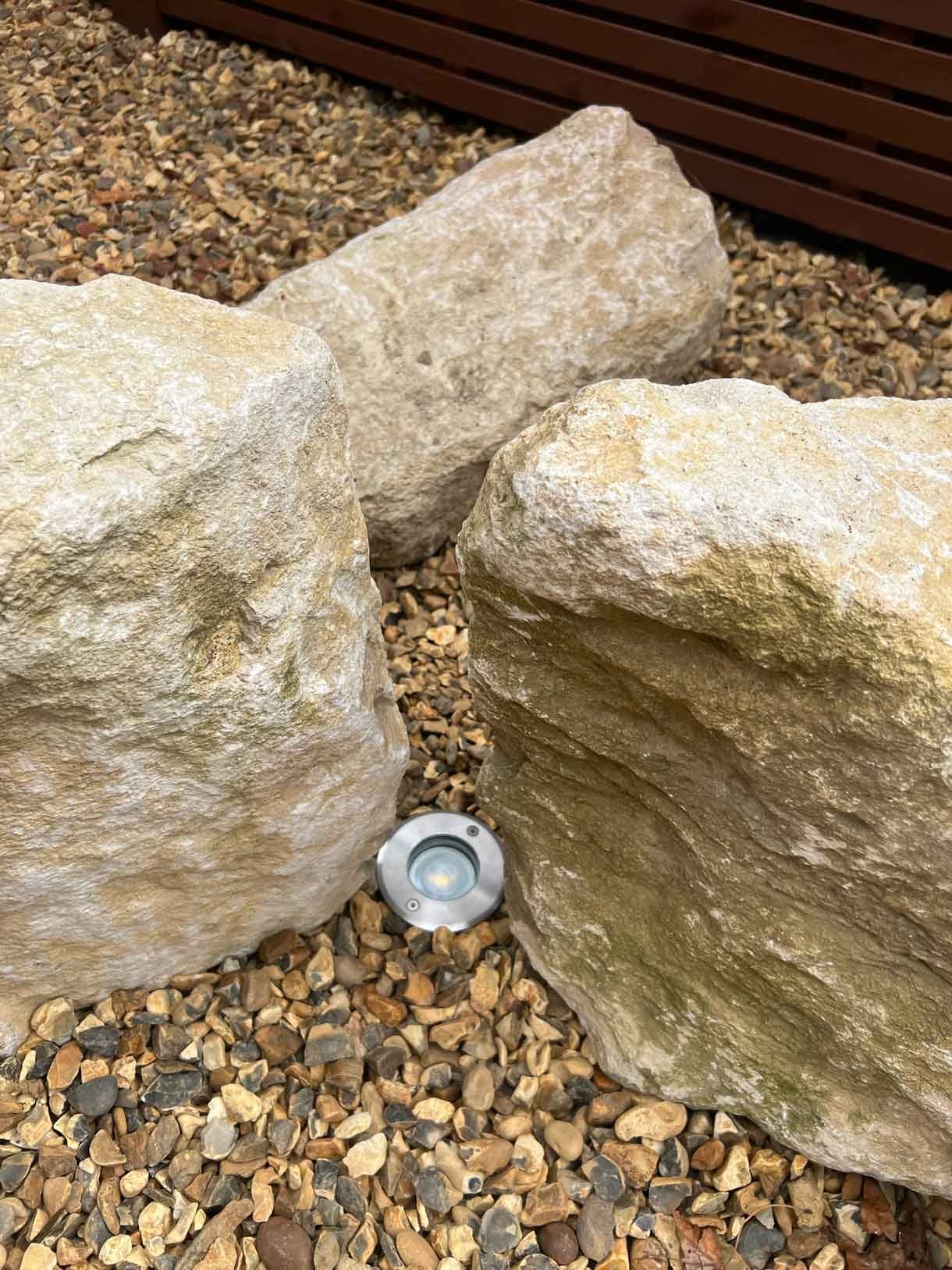 A gravel garden with plants and boulders, a water feature and stepping stones.