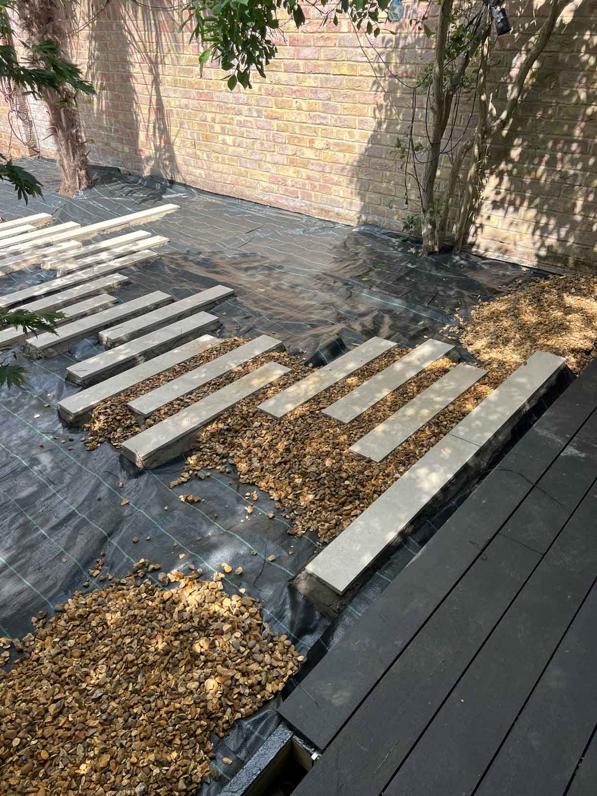 A gravel garden with plants and boulders, a water feature and stepping stones.