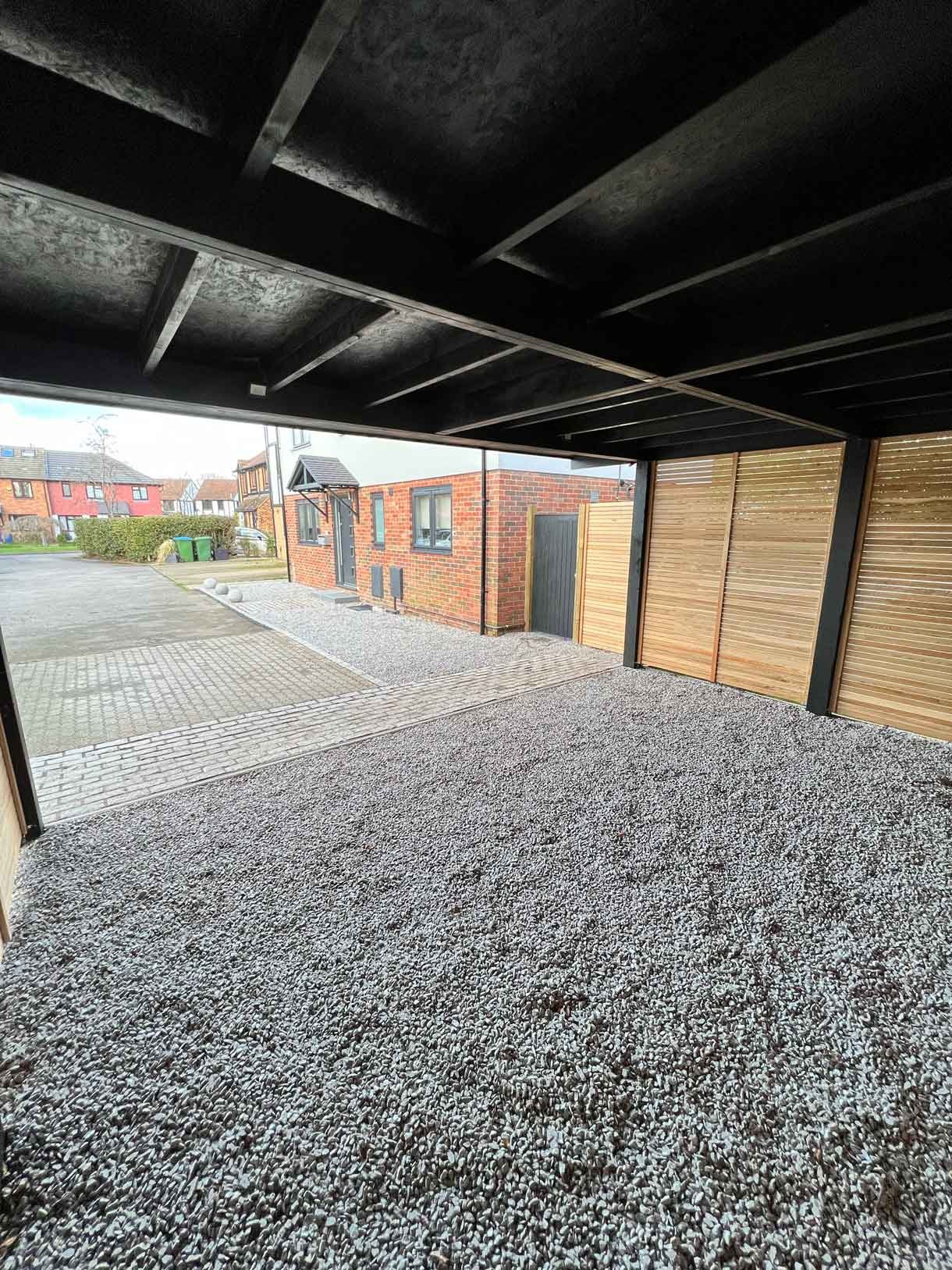 A carport made from Siberian larch panels and a gravel drive to house the clients vehicles.