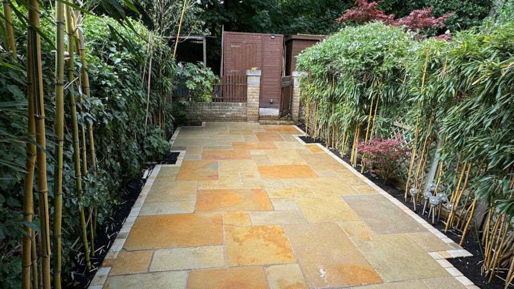 Indian sandstone paving in warm buff tones with bamboo screening and planting border