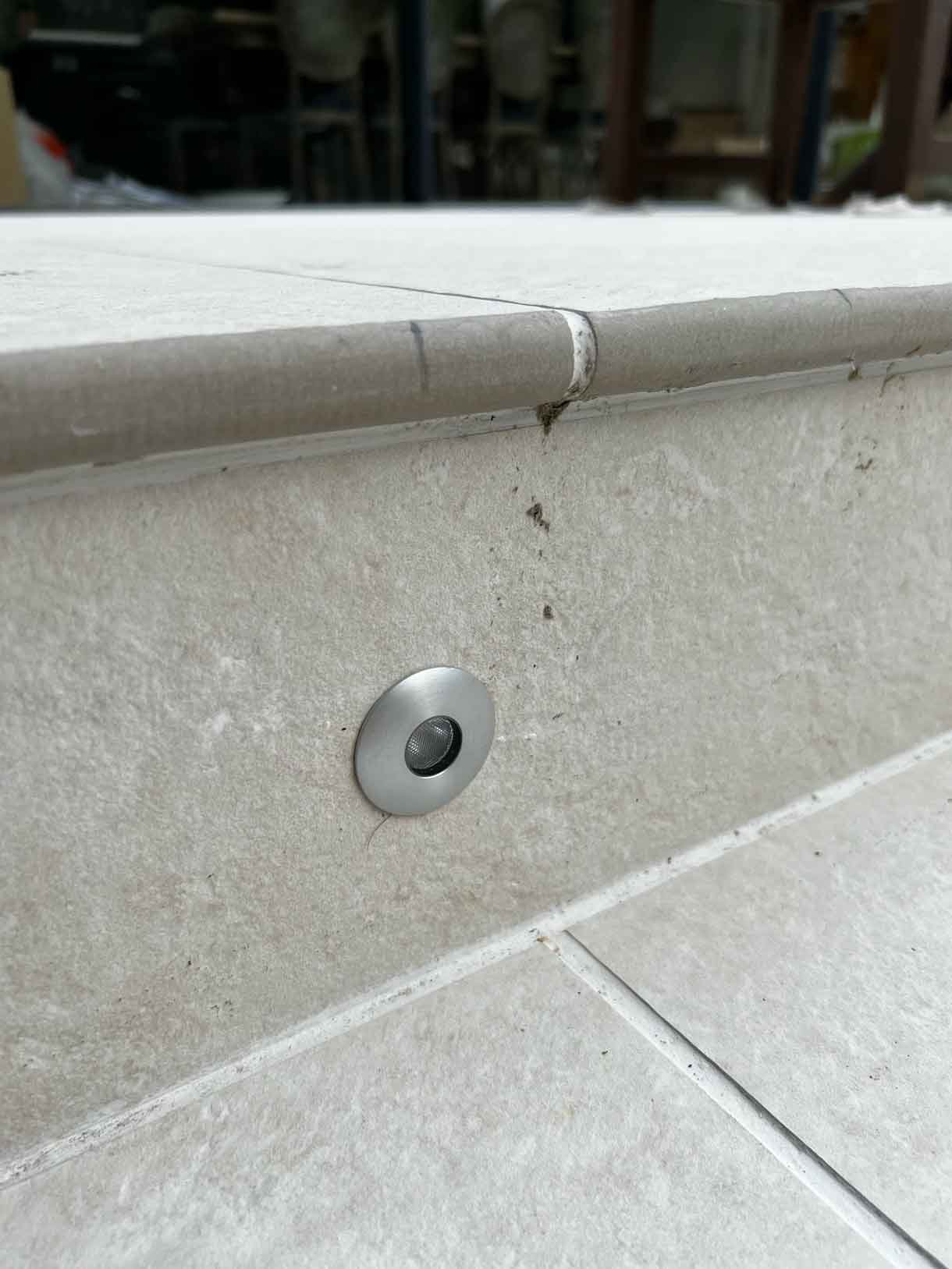 Recessed light into riser of the patio step in white porcelain