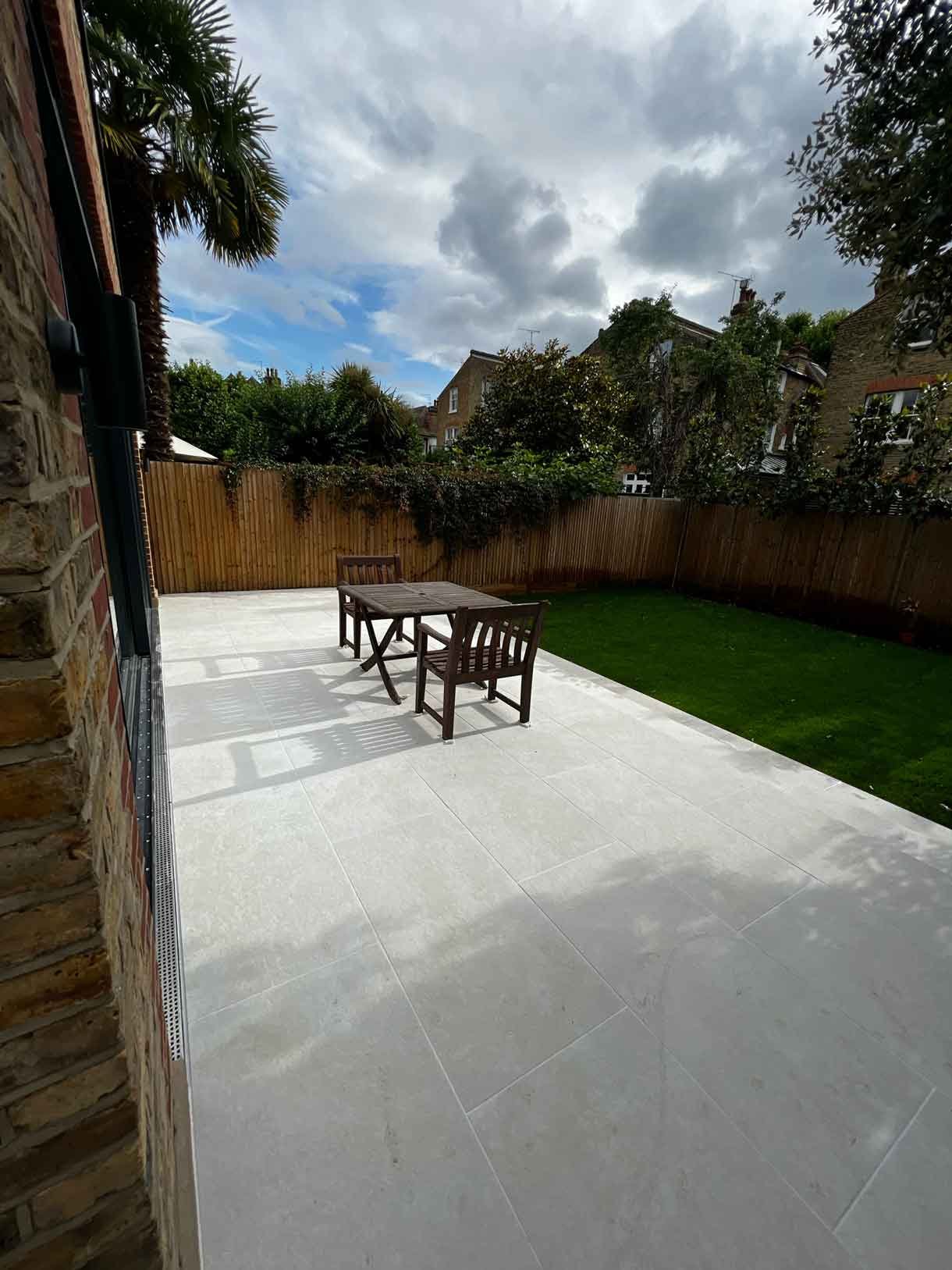 A raised patio of a new brick extension in Putney, London complete with green lawn.