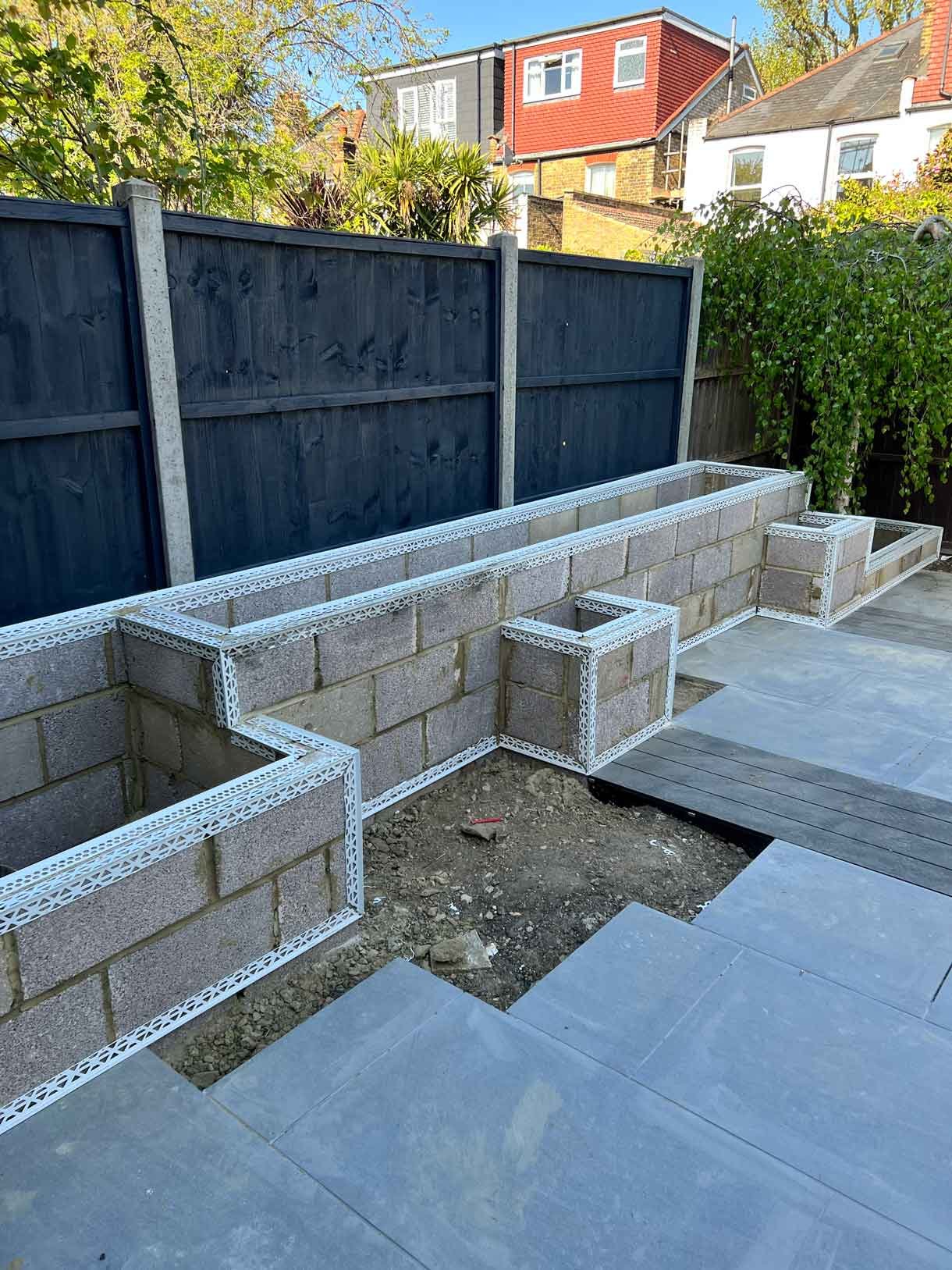 Garden redesign, using porcelain and composite decking and white rendered planters in Ealing, West London.