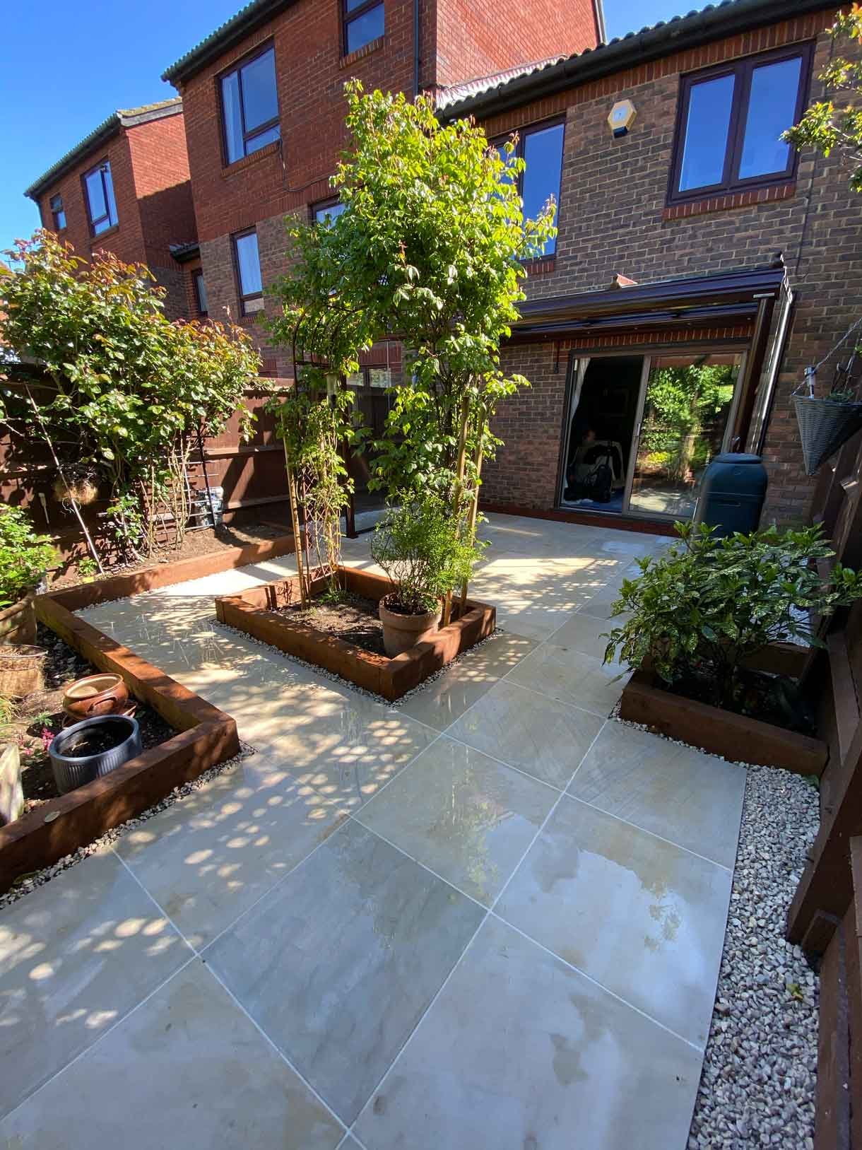 A small courtyard garden in Hammersmith. With sandstone paving and a glass sided pergola.