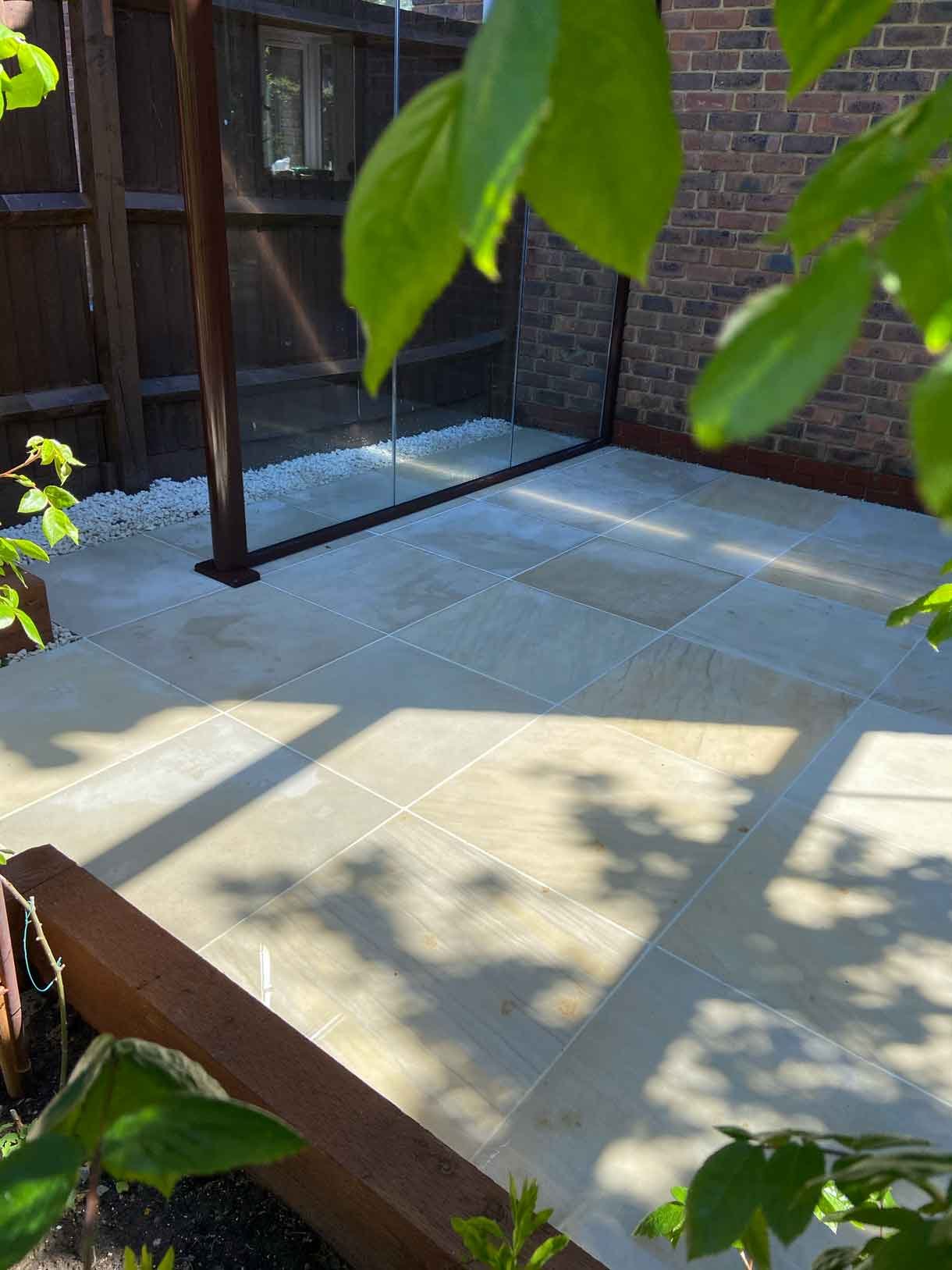 A small courtyard garden in Hammersmith. With sandstone paving and a glass sided pergola.