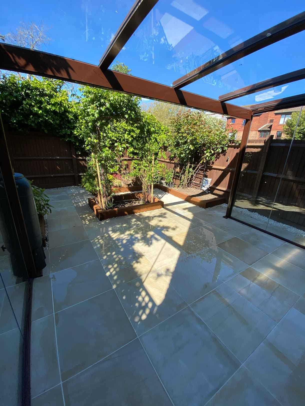 A small courtyard garden in Hammersmith. With sandstone paving and a glass sided pergola.