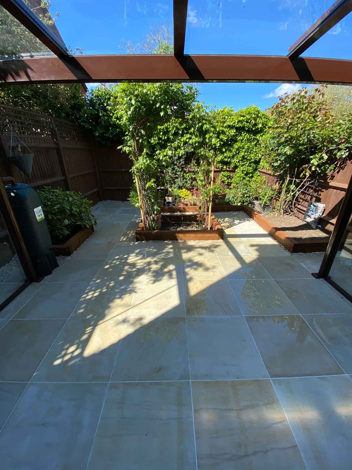 A small courtyard garden in Hammersmith. With sandstone paving and a glass sided pergola.