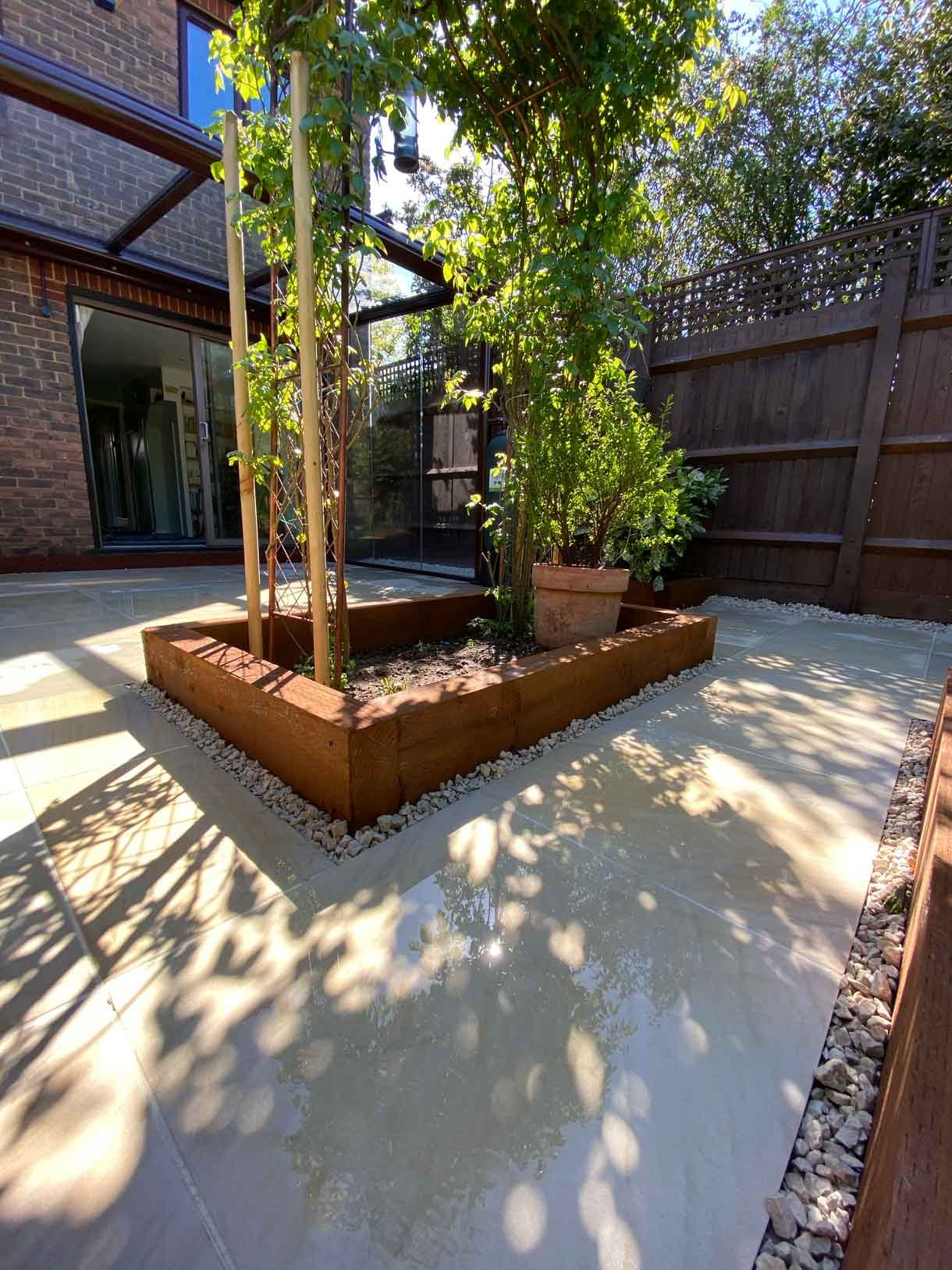 A small courtyard garden in Hammersmith. With sandstone paving and a glass sided pergola.
