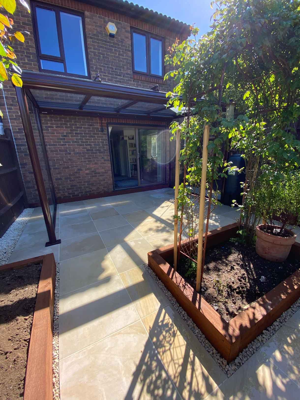 A small courtyard garden in Hammersmith. With sandstone paving and a glass sided pergola.
