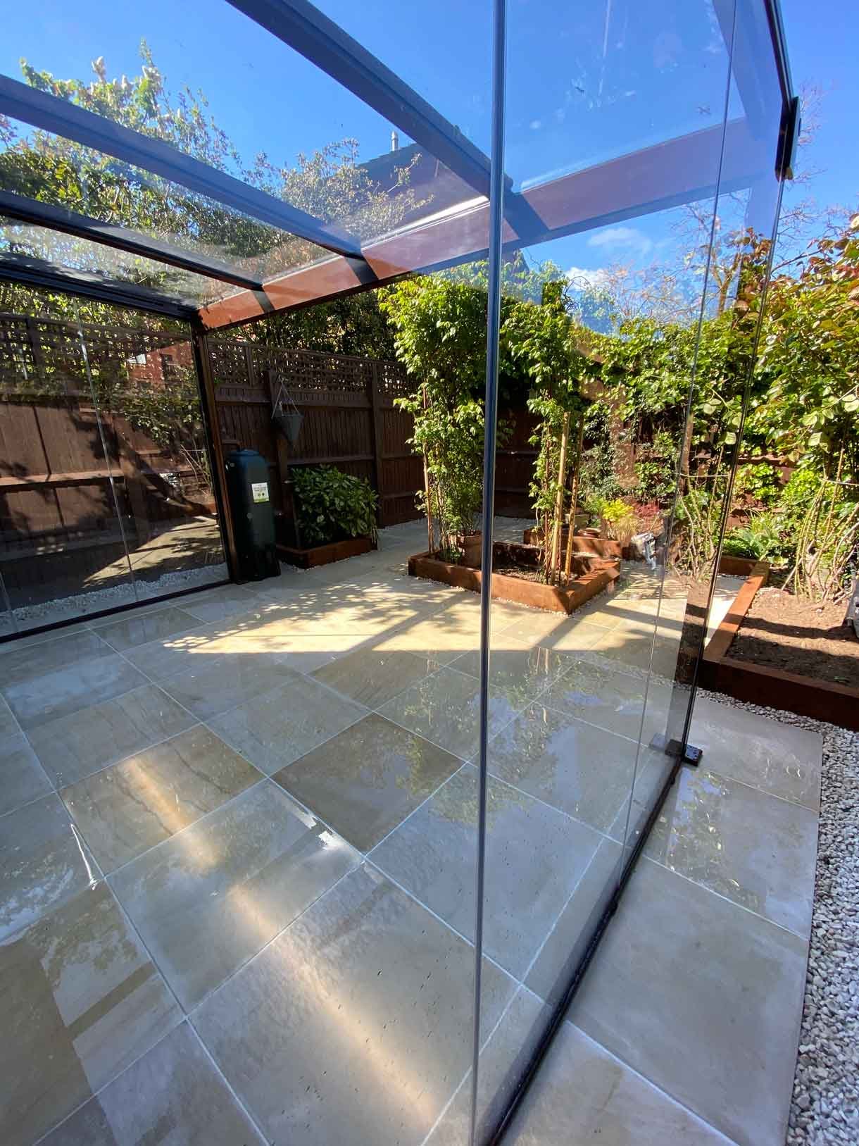A small courtyard garden in Hammersmith. With sandstone paving and a glass sided pergola.