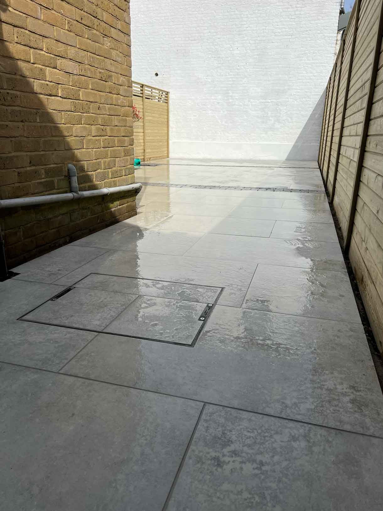A garden completely paved in porcelain tiles and planted in cut outs of the tiles and raised planters.