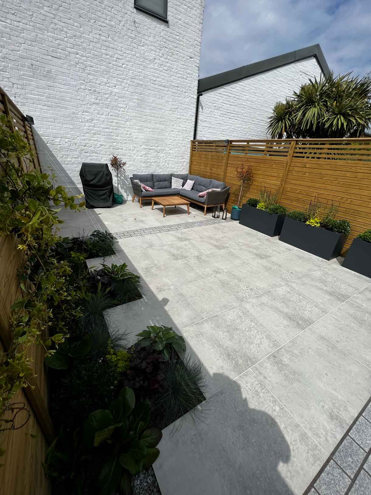 A garden completely paved in porcelain tiles and planted in cut outs of the tiles and raised planters.
