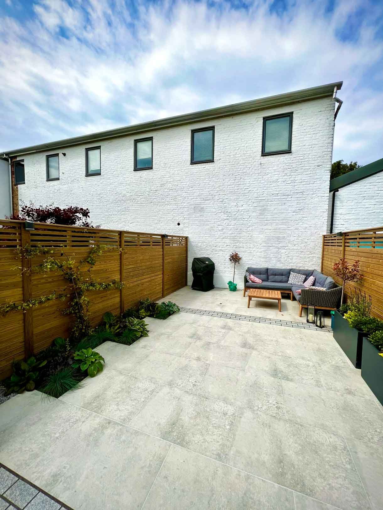 A garden completely paved in porcelain tiles and planted in cut outs of the tiles and raised planters.