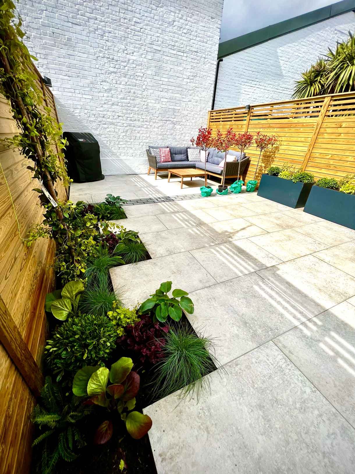 A garden completely paved in porcelain tiles and planted in cut outs of the tiles and raised planters.