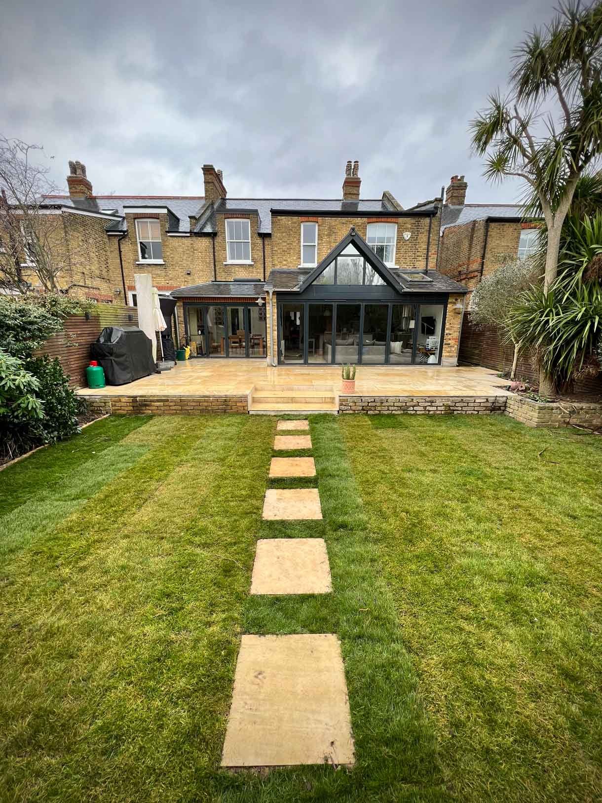 A new sandstone patio to complement the new house extension with steps on to the new lawn.