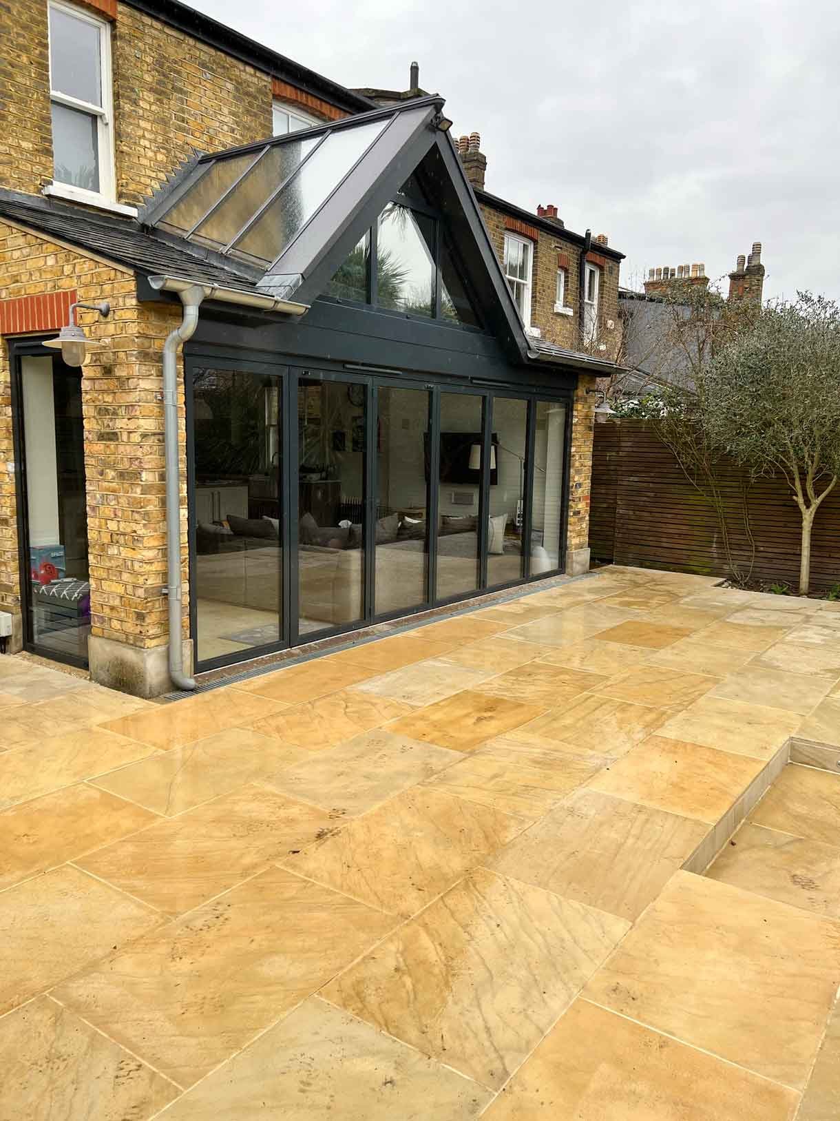 A new sandstone patio to complement the new house extension with steps on to the new lawn.