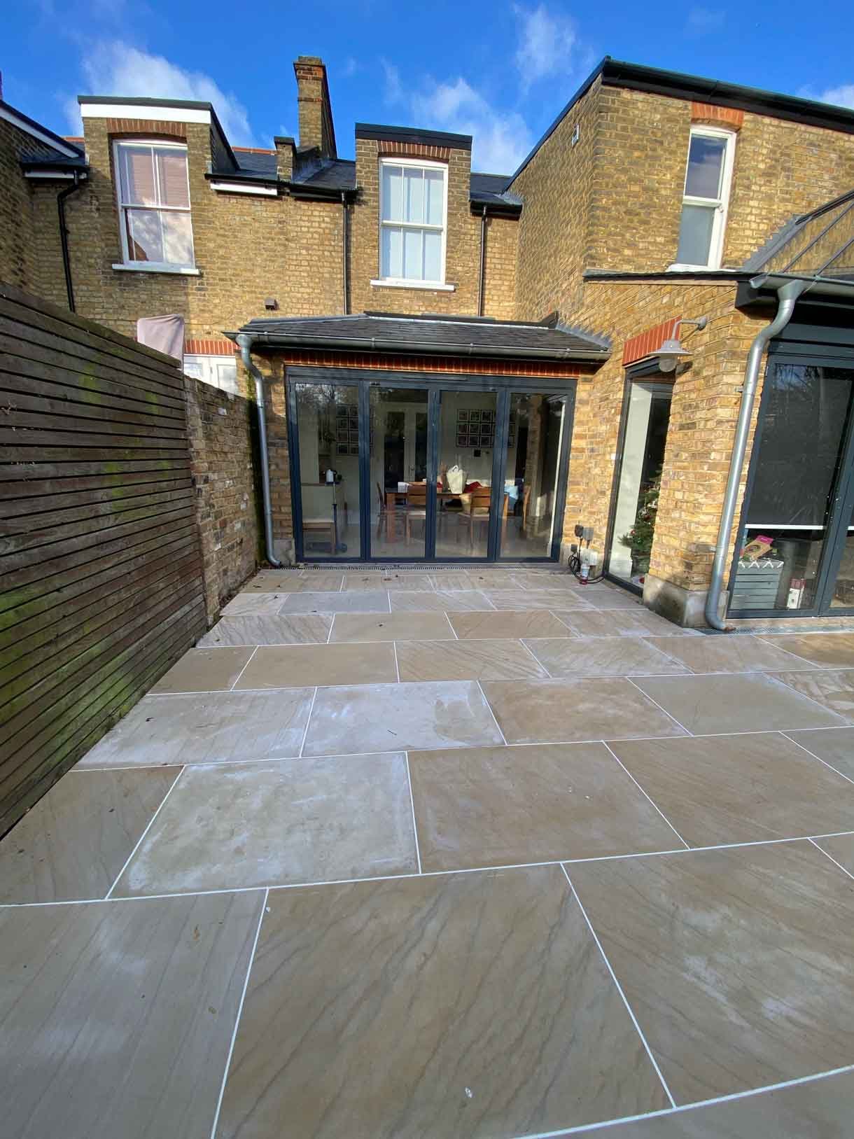 A new sandstone patio to complement the new house extension with steps on to the new lawn.