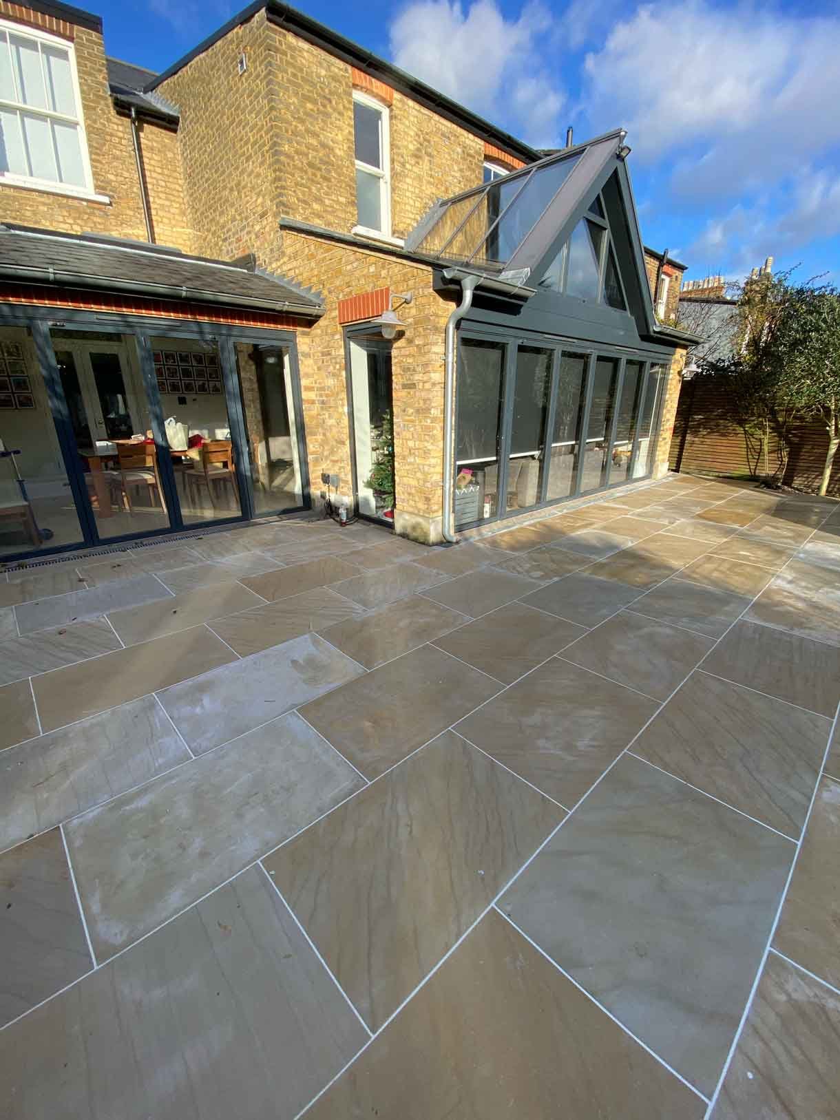 A new sandstone patio to complement the new house extension with steps on to the new lawn.