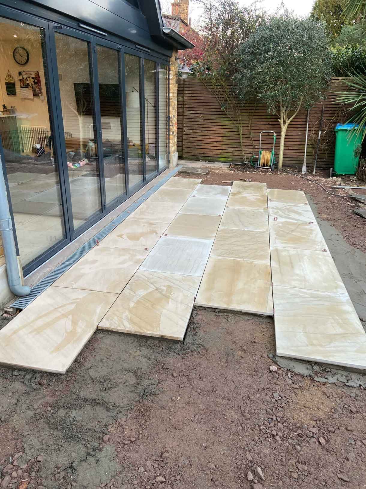 A new sandstone patio to complement the new house extension with steps on to the new lawn.