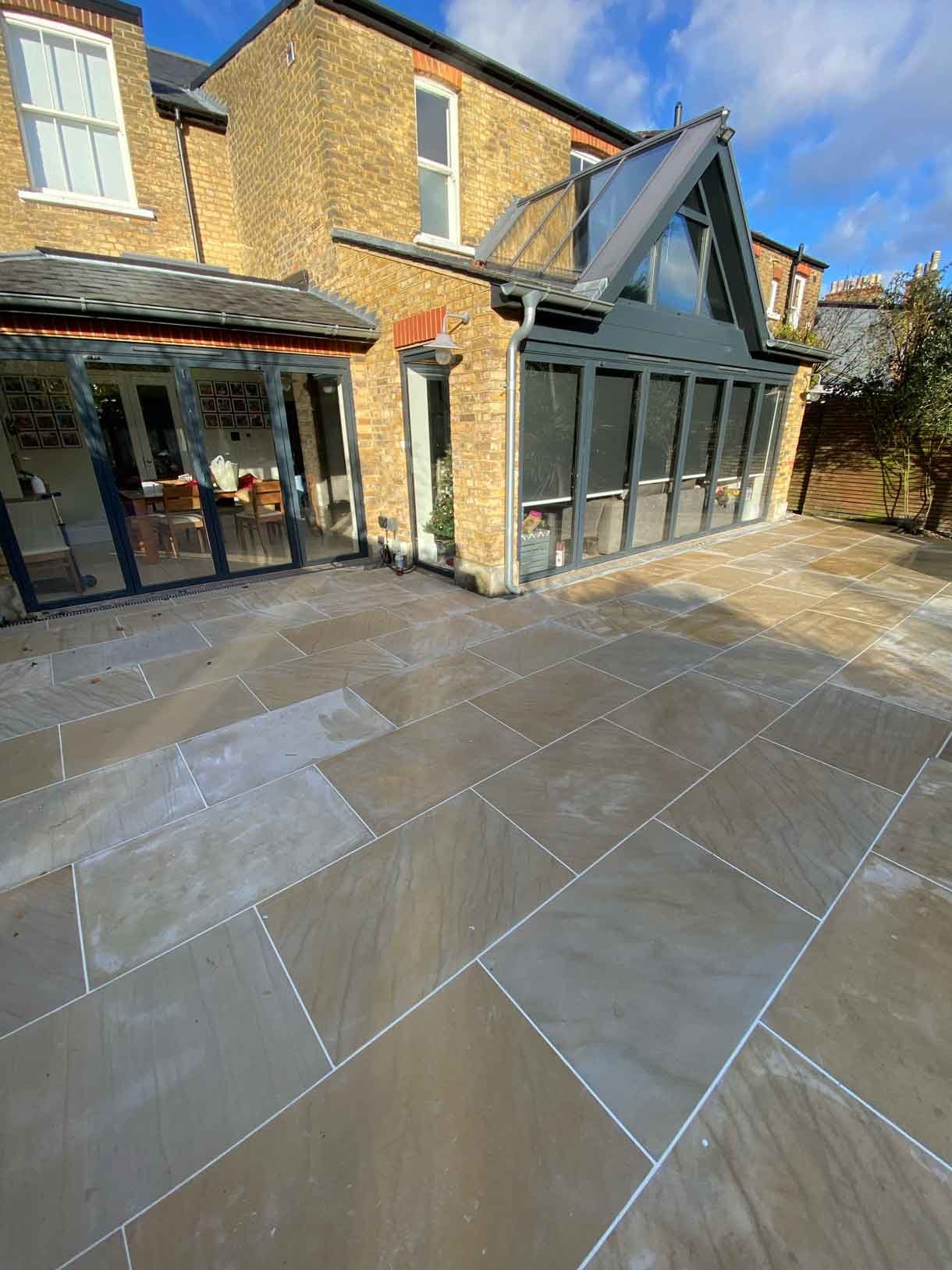 A new sandstone patio to complement the new house extension with steps on to the new lawn.