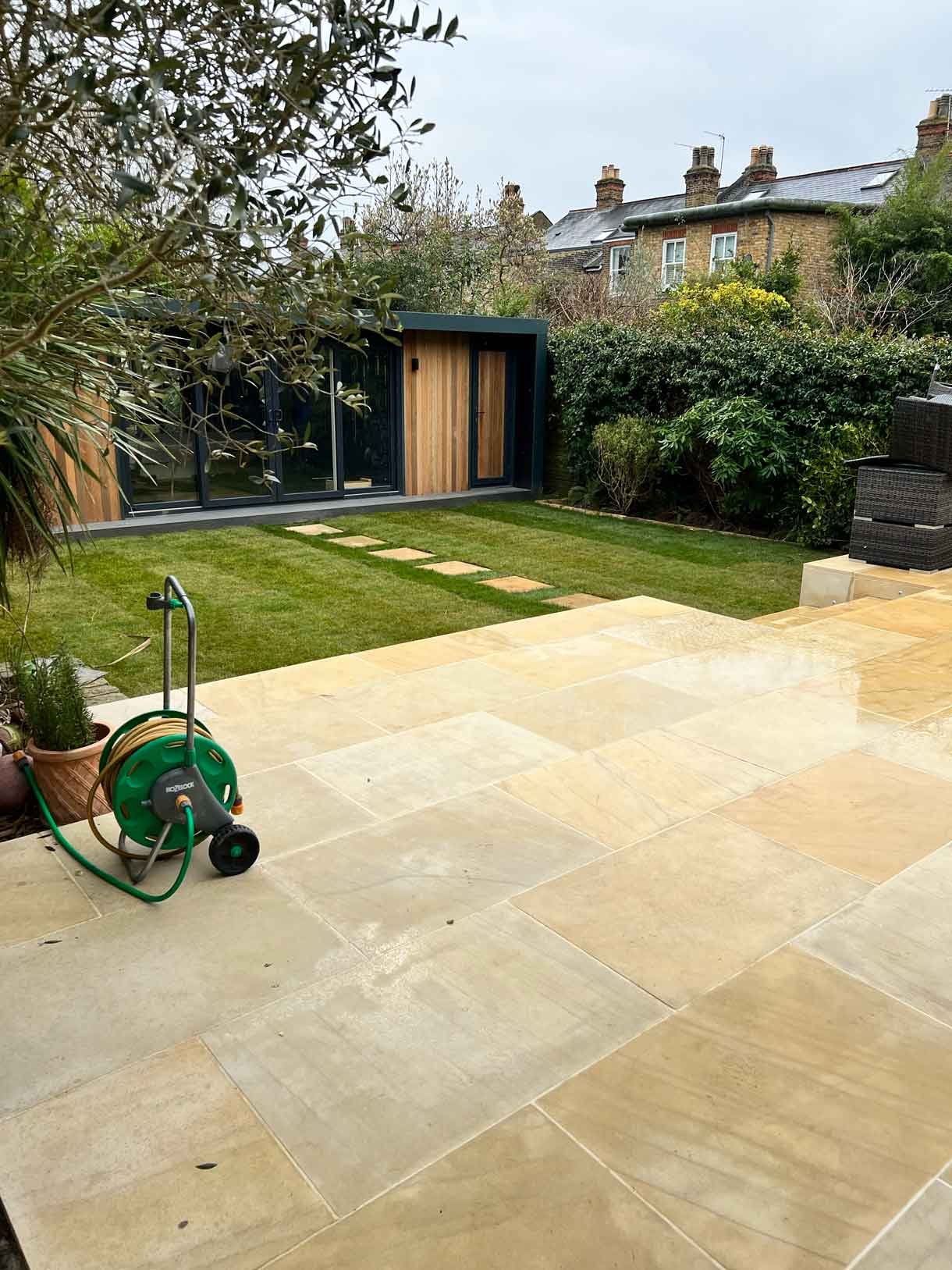 A new sandstone patio to complement the new house extension with steps on to the new lawn.