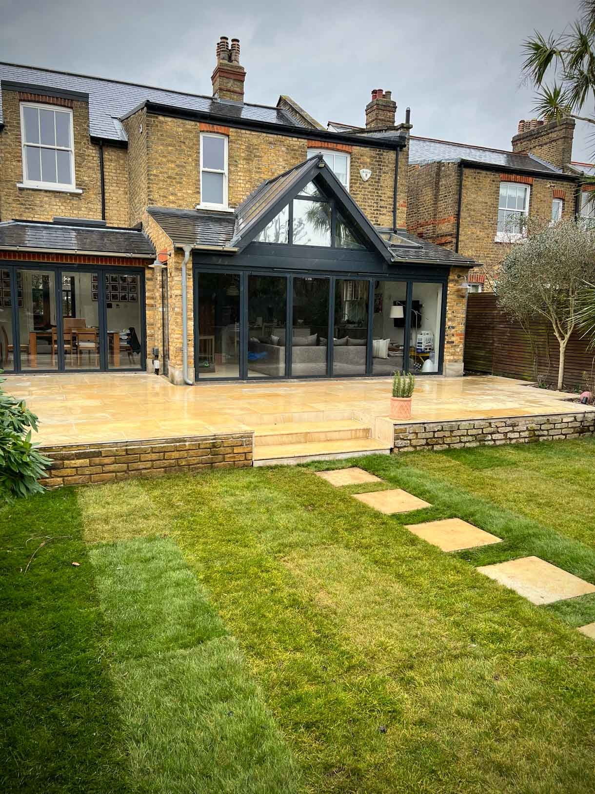 A new sandstone patio to complement the new house extension with steps on to the new lawn.