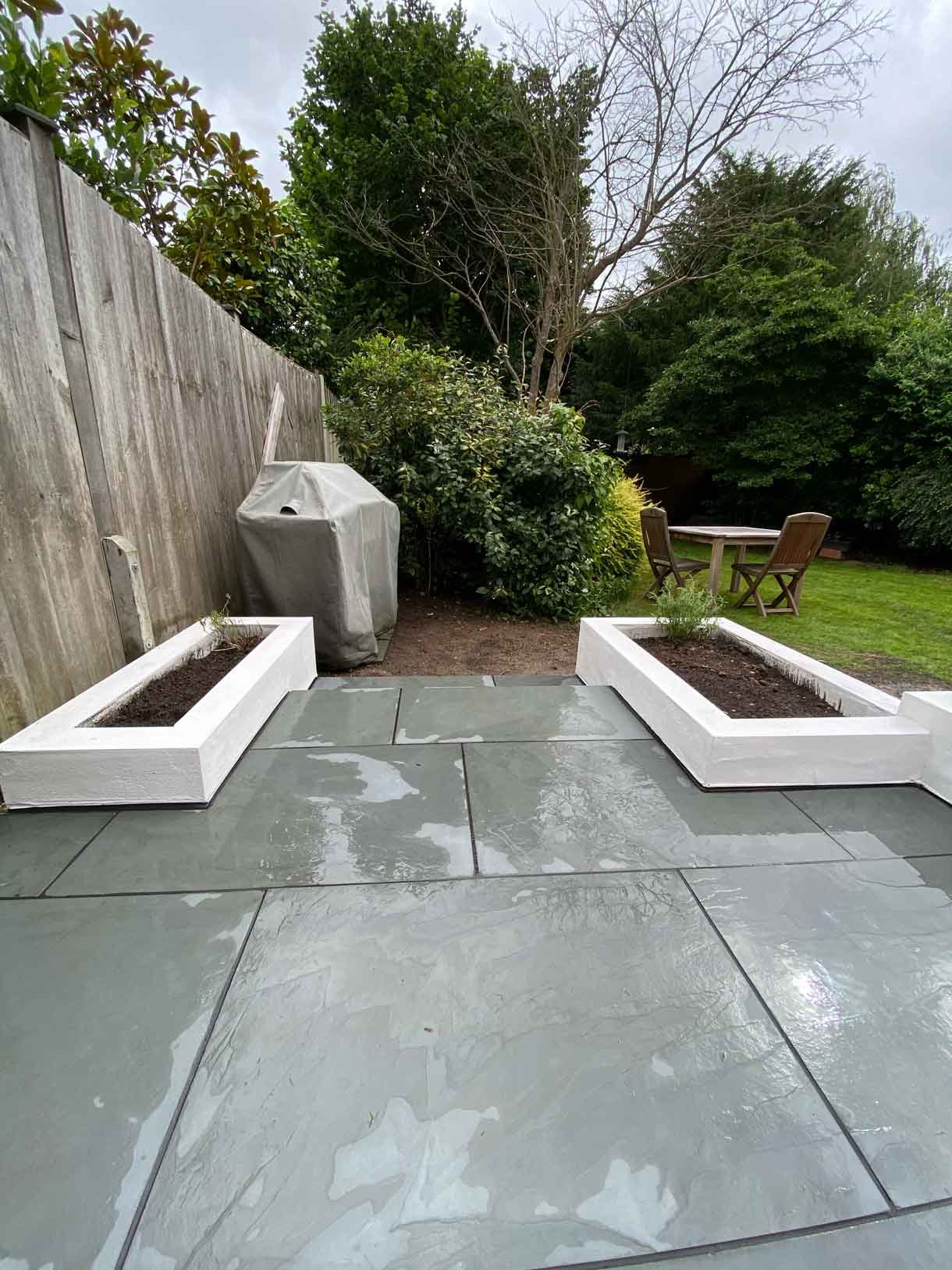 A raised grey slate patio in Teddington, with white rendered planters.