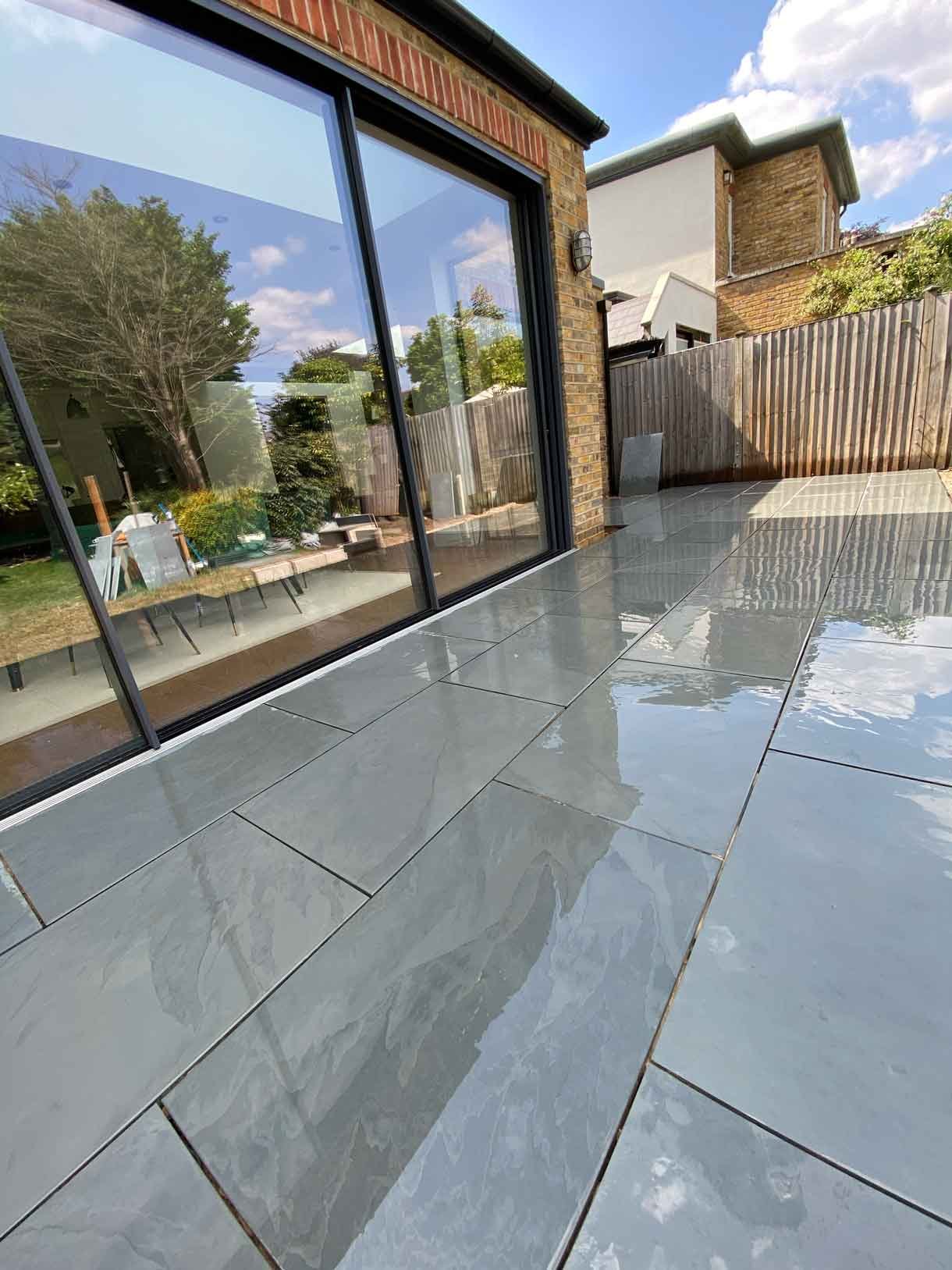 A raised grey slate patio in Teddington, with white rendered planters.