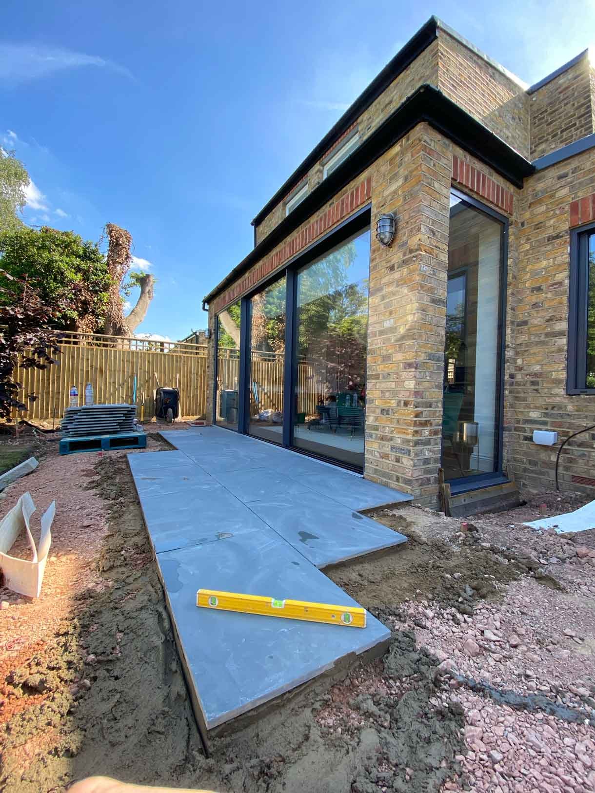 A raised grey slate patio in Teddington, with white rendered planters.