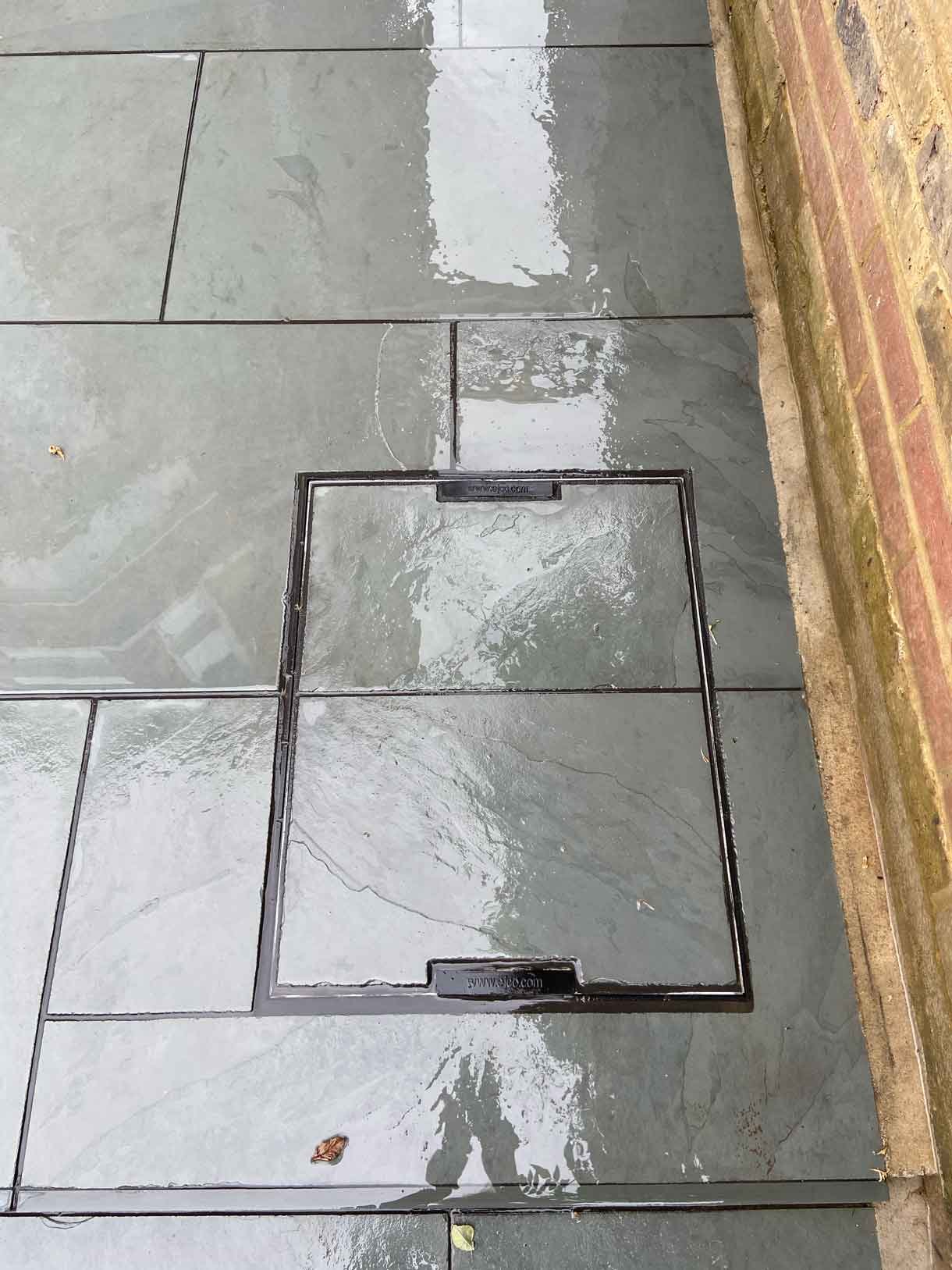 A raised grey slate patio in Teddington, with white rendered planters.