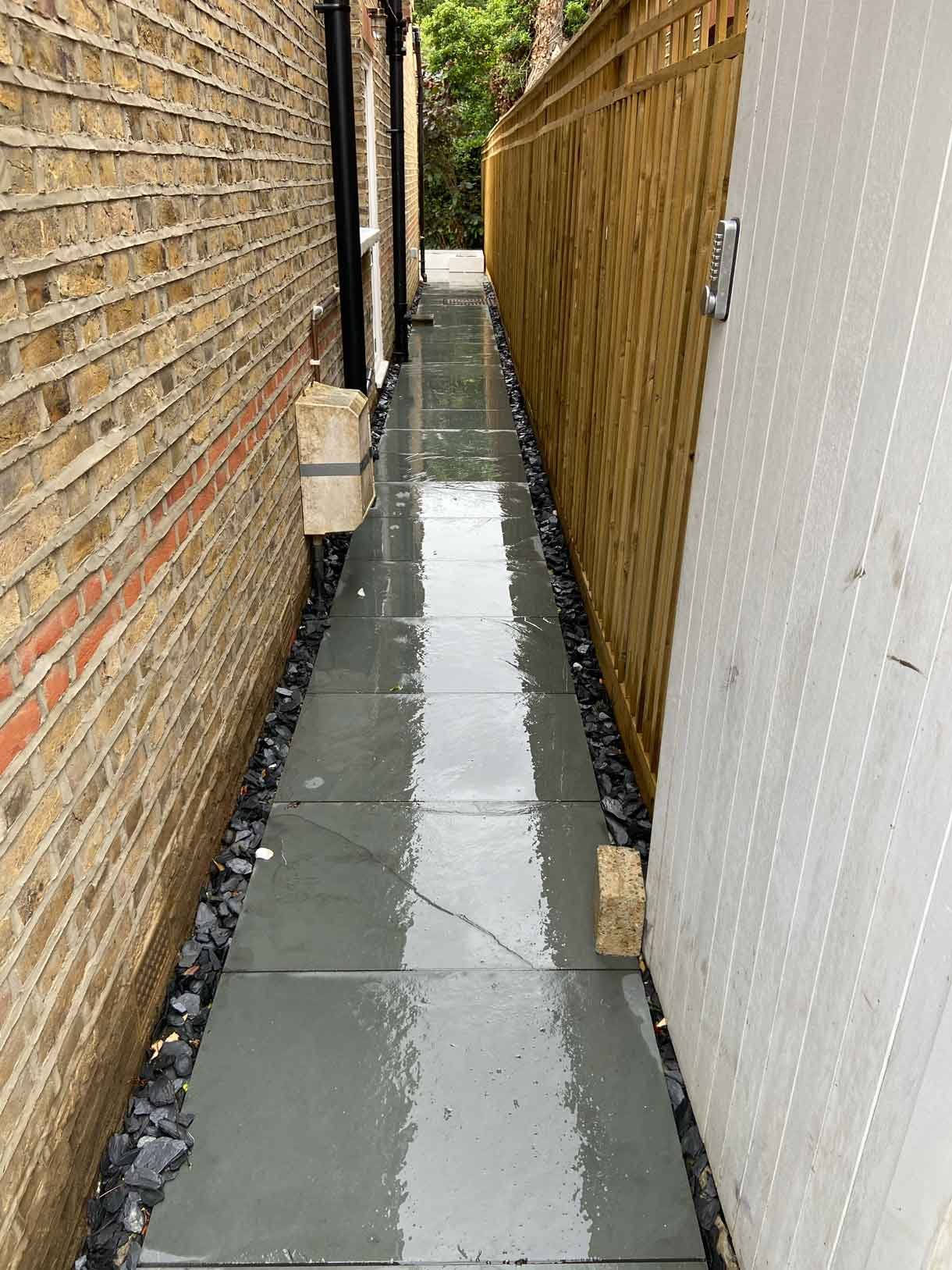 A raised grey slate patio in Teddington, with white rendered planters.