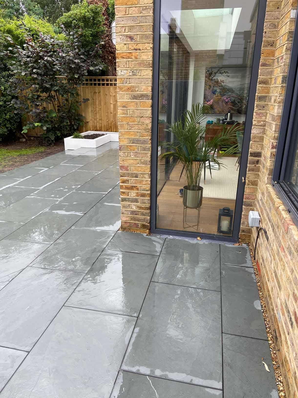 A raised grey slate patio in Teddington, with white rendered planters.