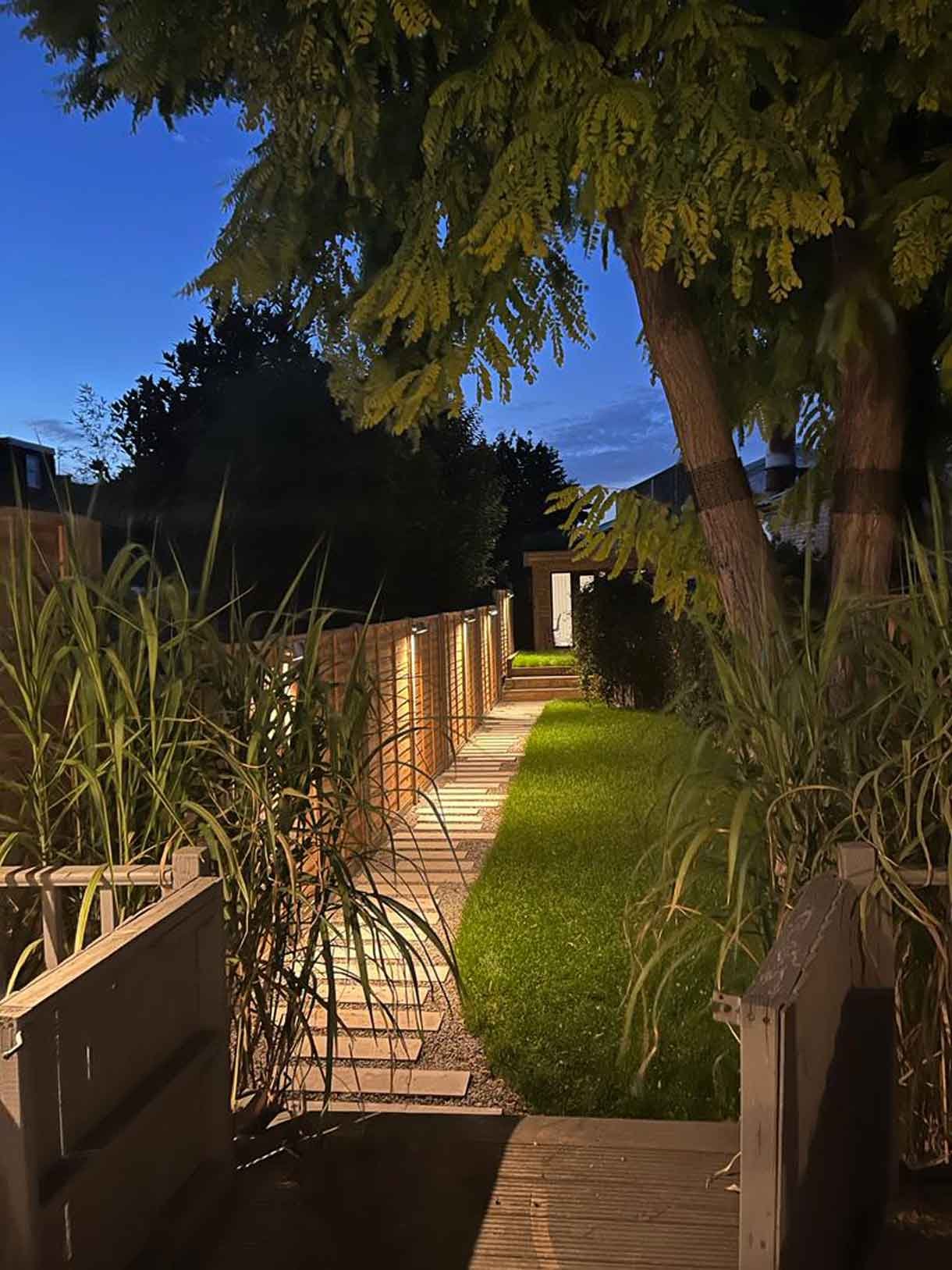 The long garden and path illuminated with lights.