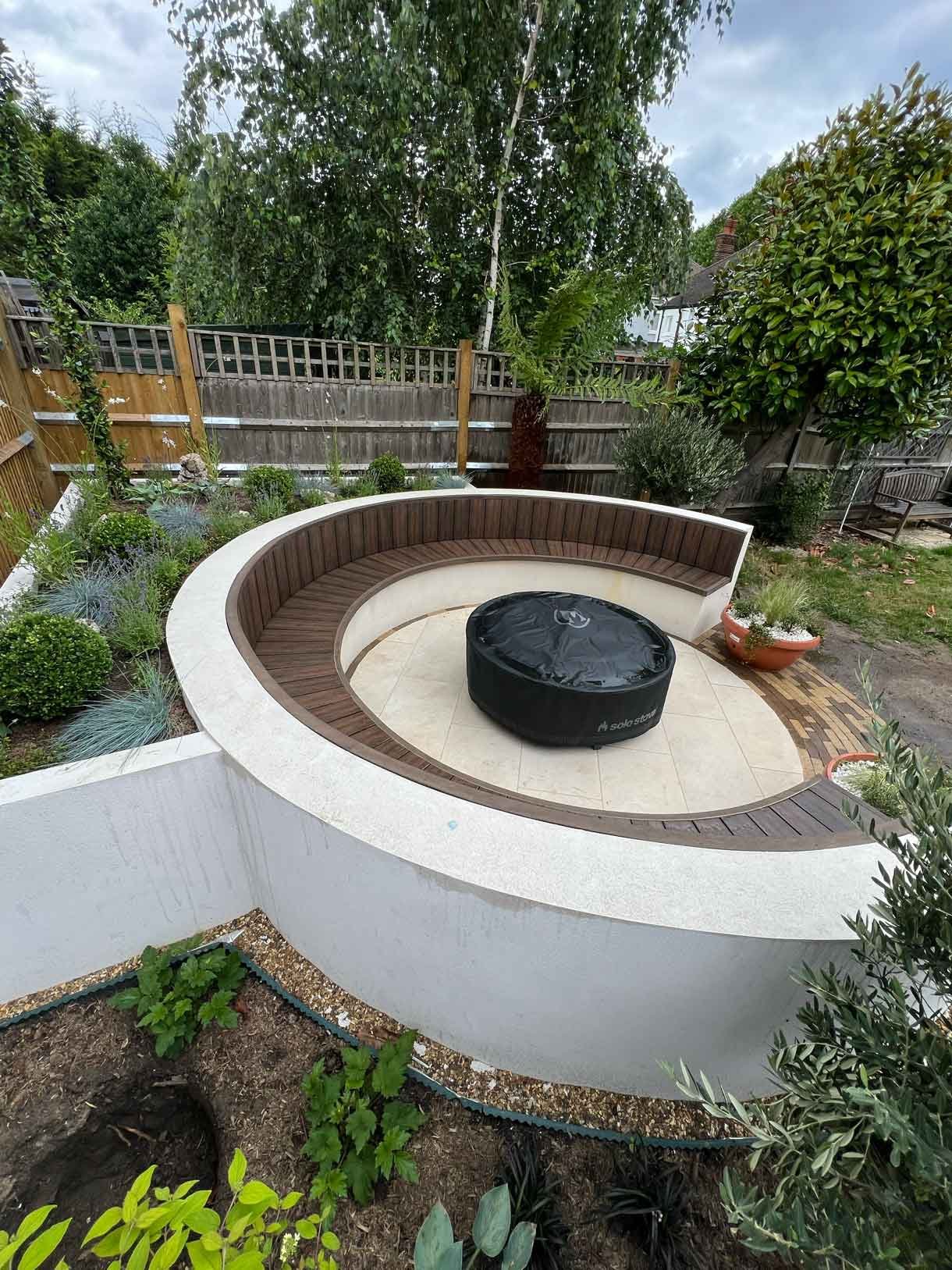 A rendered circular seating area also made from composite with a fire pit in the middle.