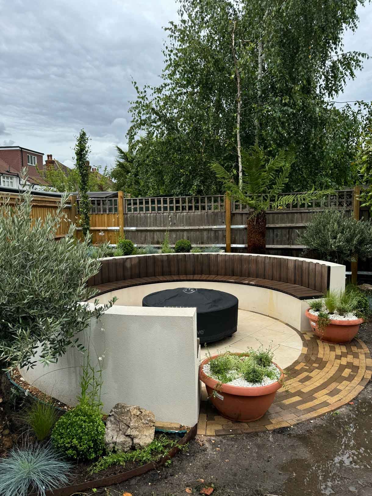 A rendered circular seating area also made from composite with a fire pit in the middle.