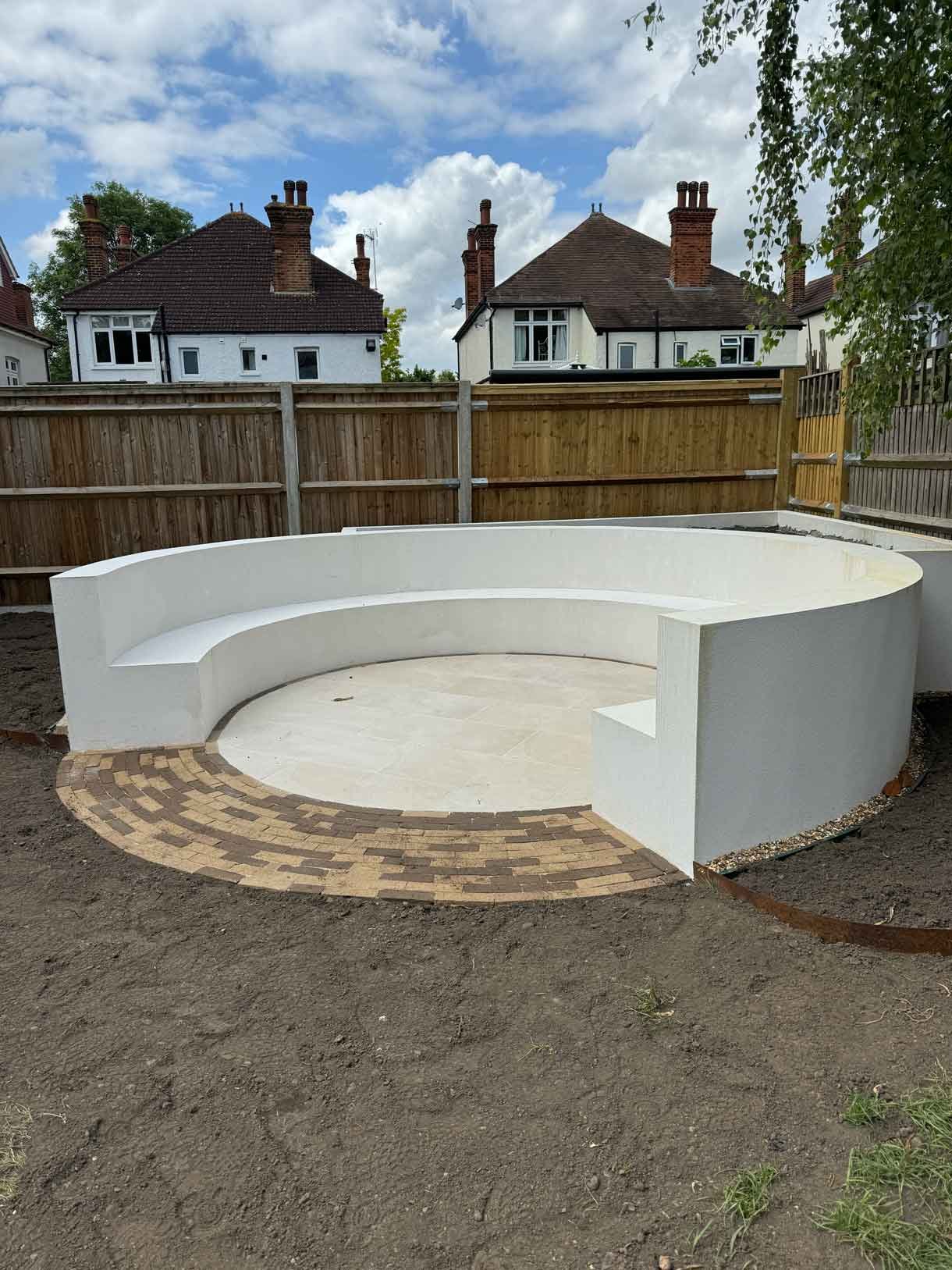 A rendered circular seating area also made from composite with a fire pit in the middle.