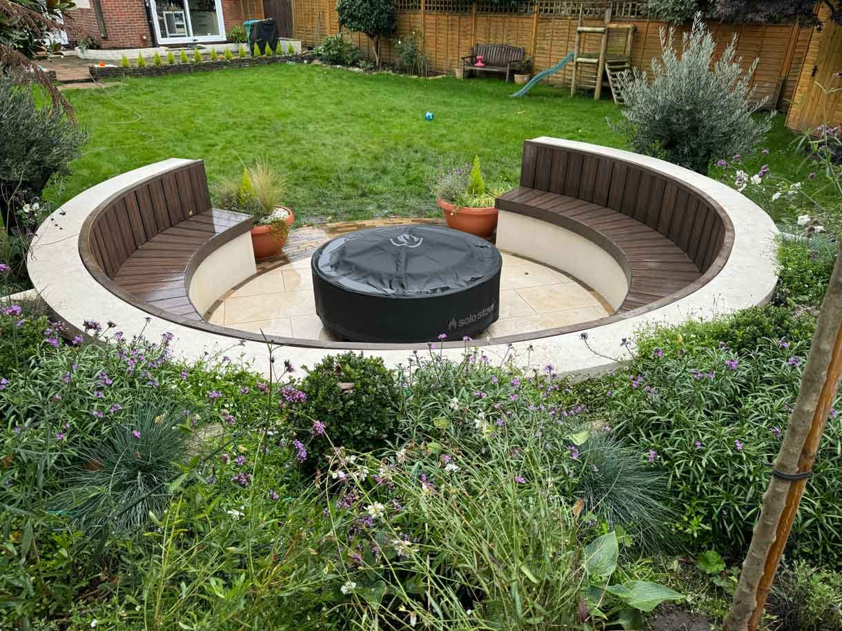 A rendered circular seating area also made from composite with a fire pit in the middle.