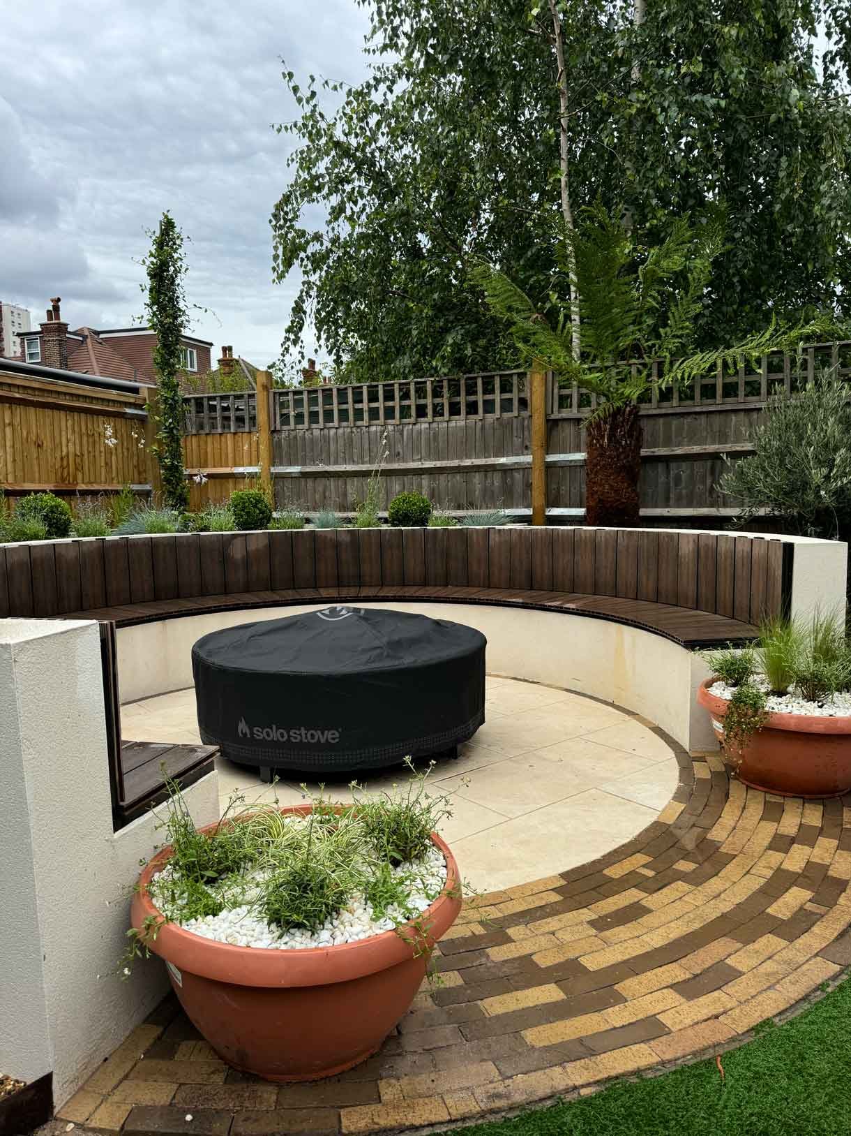 A rendered circular seating area also made from composite with a fire pit in the middle.