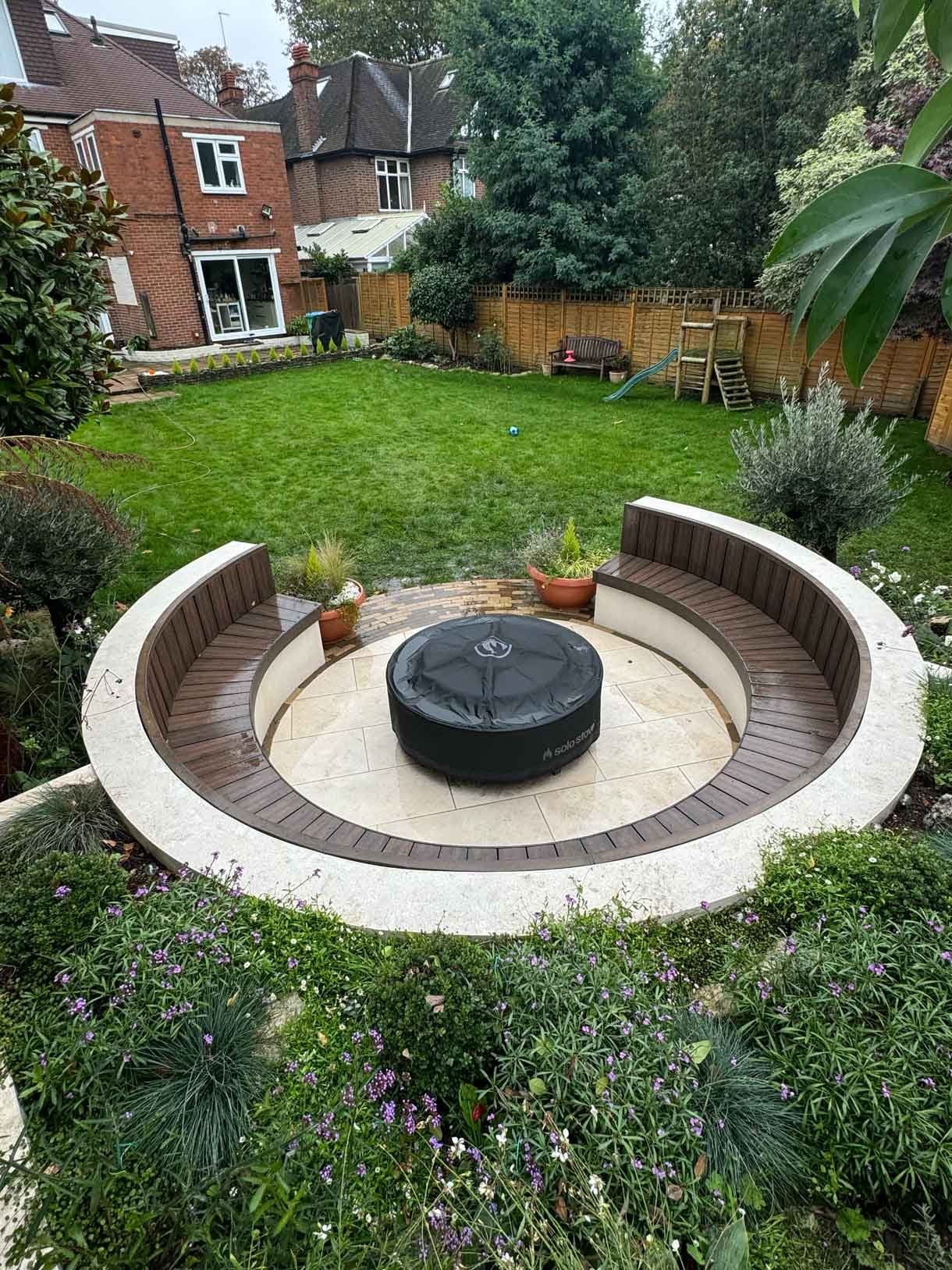 A rendered circular seating area also made from composite with a fire pit in the middle.