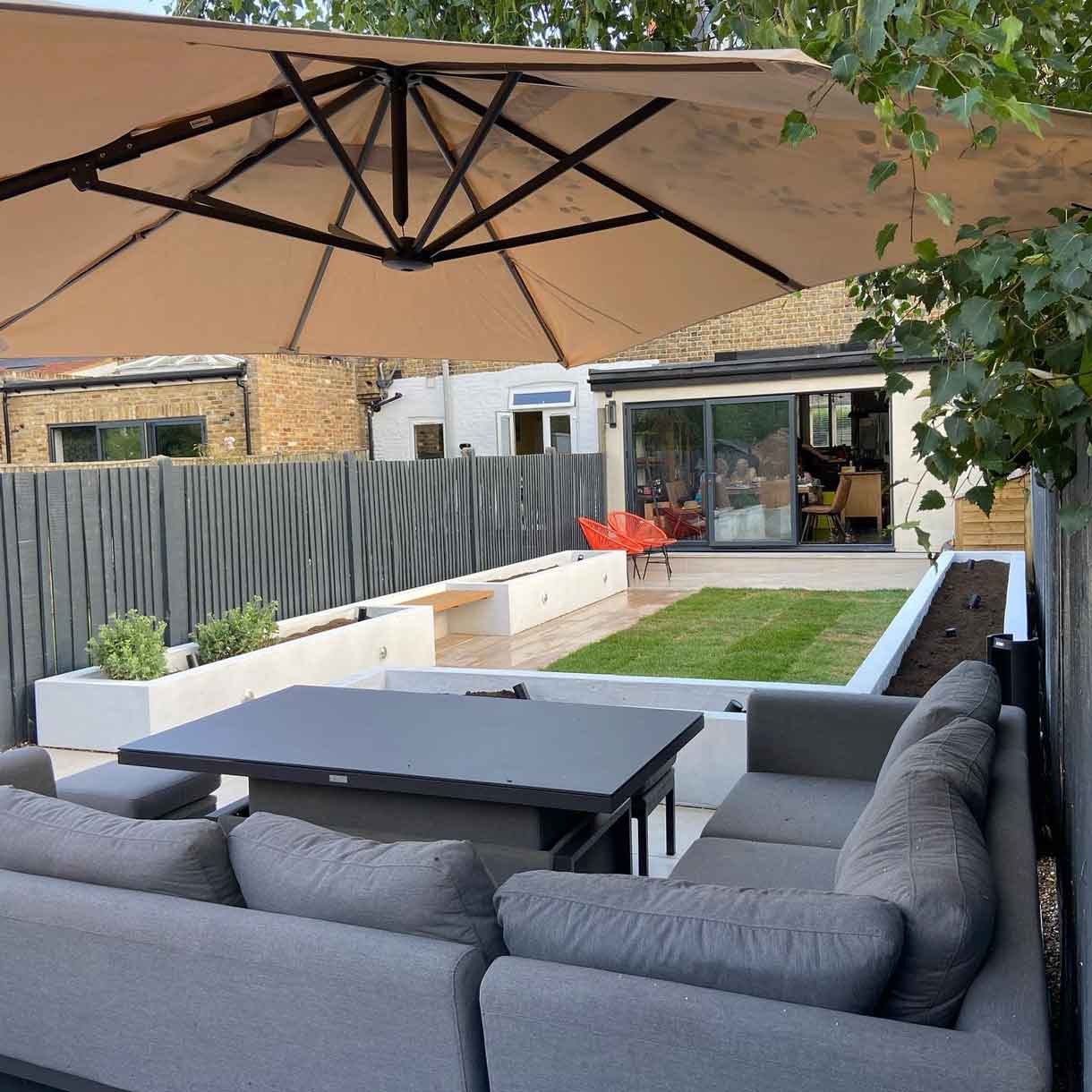 A garden redesign in Tooting, with raised planters, seating area and raised patio at the back of the garden with garden lighting throughout.