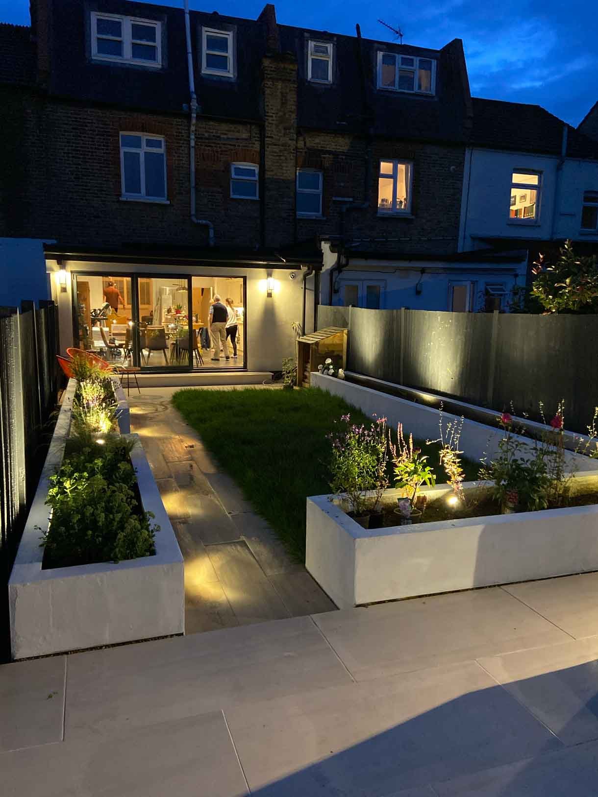 A garden redesign in Tooting, with raised planters, seating area and raised patio at the back of the garden with garden lighting throughout.